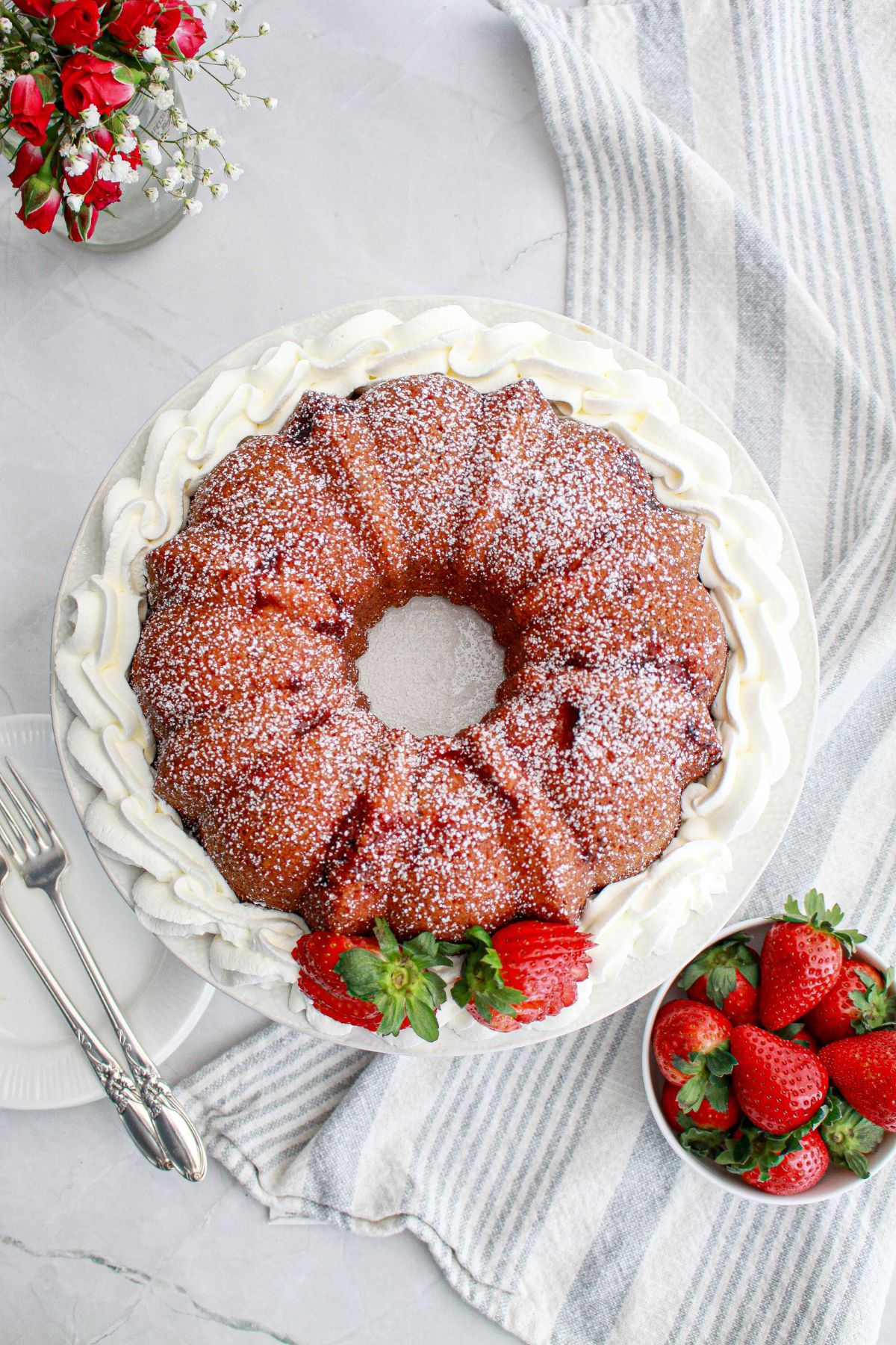 uncut strawberry bundt cake surrounded by whipped cream.