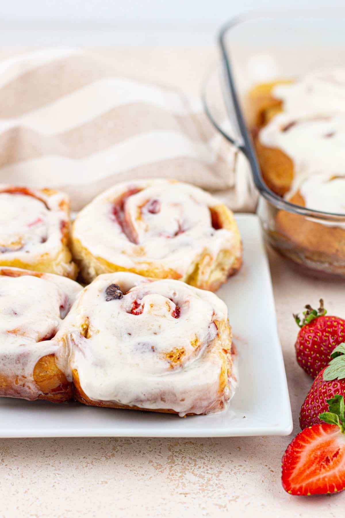 four strawberry cinnamon rolls on a plate.