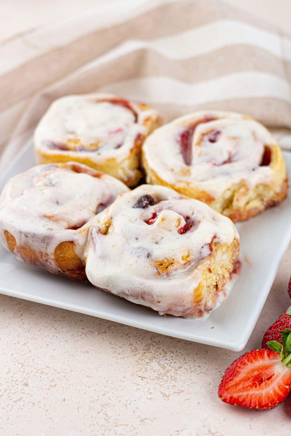 four strawberry cinnamon rolls on a plate.