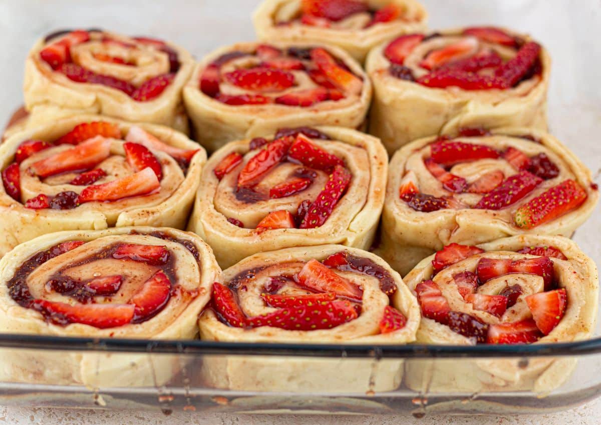 unbaked cinnamon rolls in a glass baking dish.