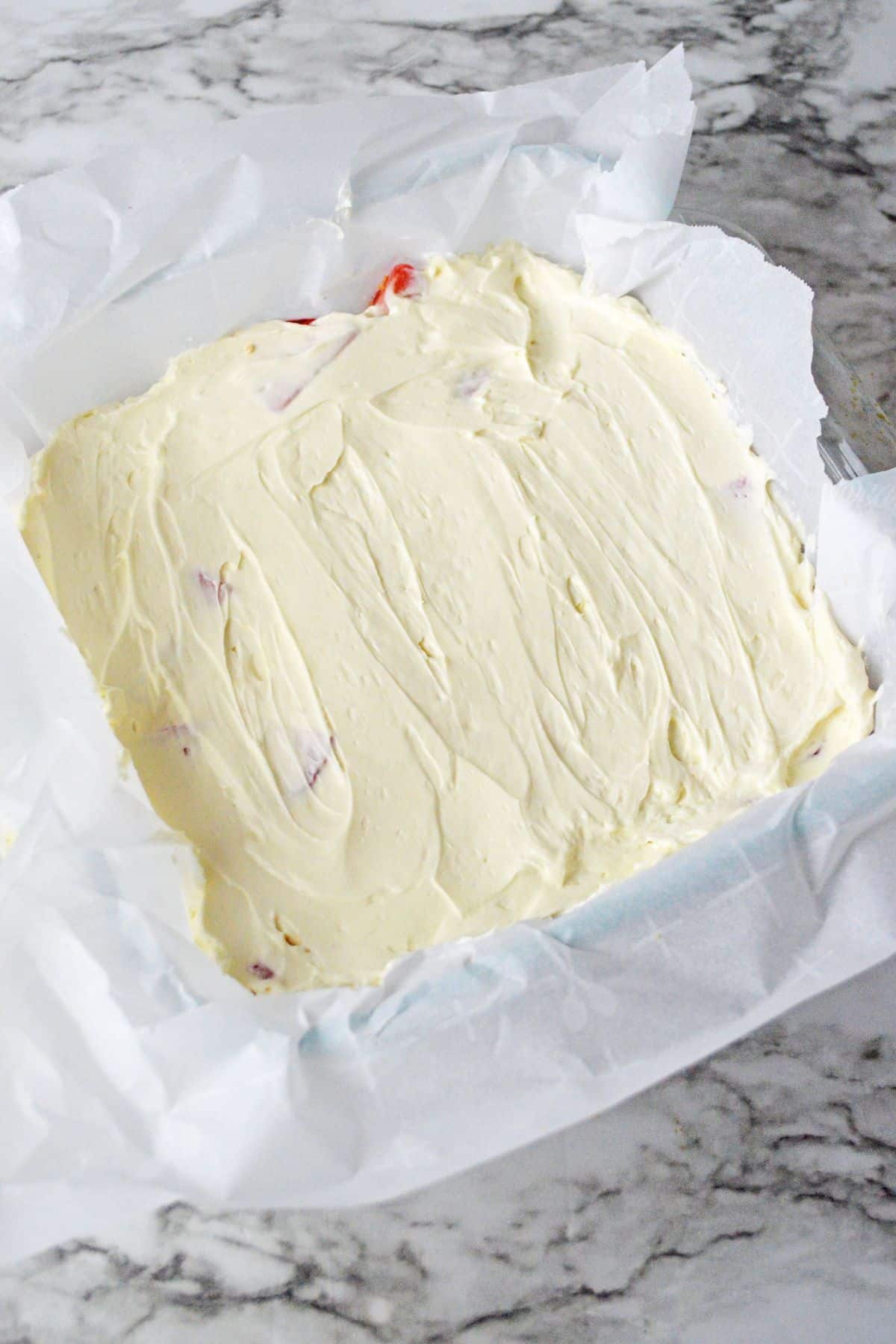 cream cheese layer being added to the top of the dessert.