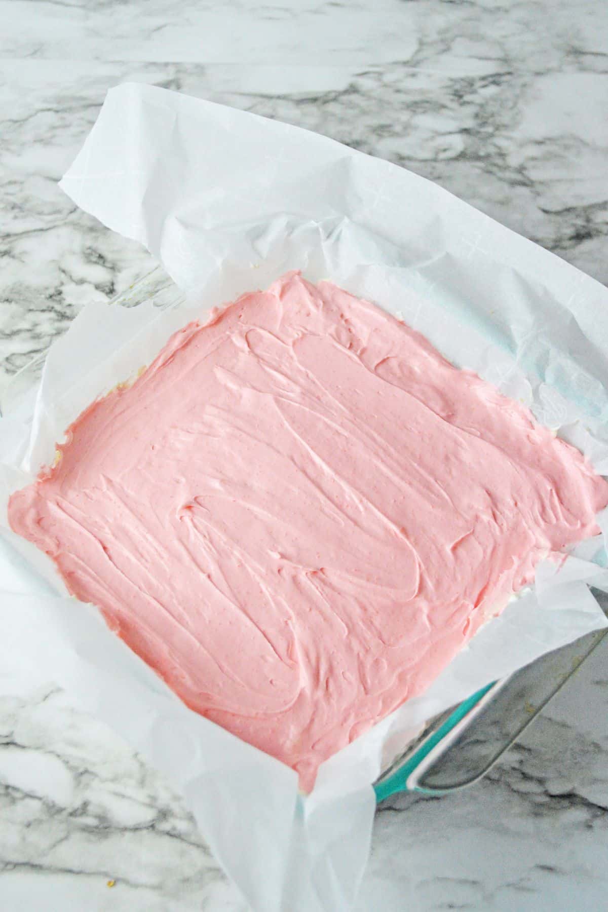 strawberry layer being added to the dessert.