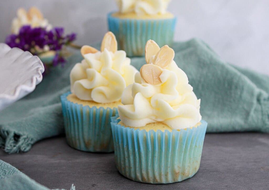 two almond cupcakes on a marble counter.