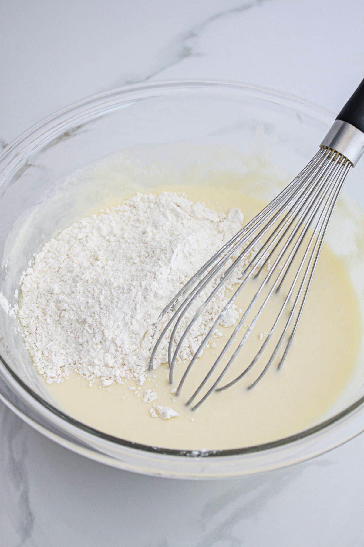 cupcake batter being mixed in a glass mixing bowl.