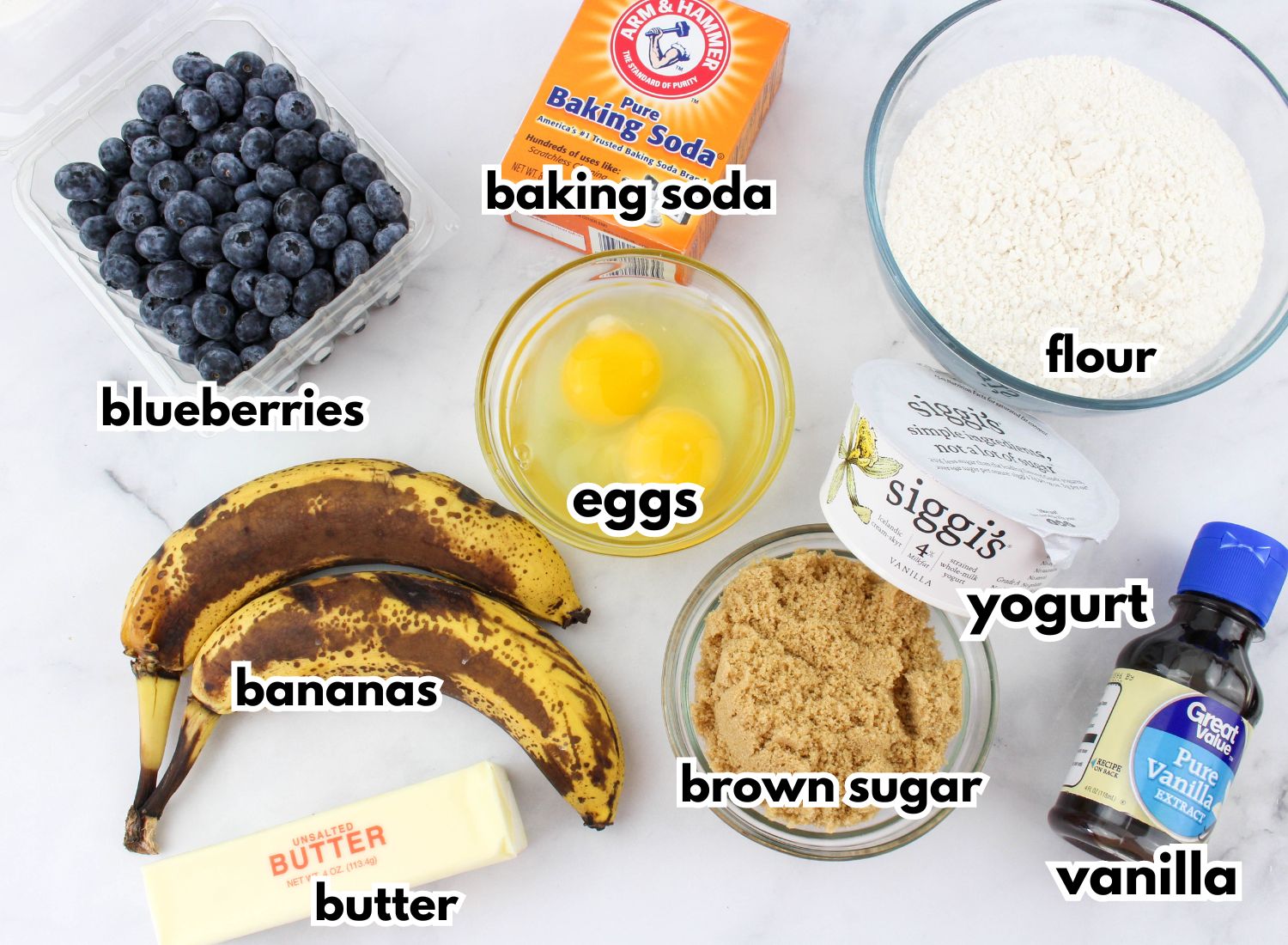 bowls of blueberries, baking soda, flour, eggs, bananas, butter, brown sugar, yogurt, and vanilla.