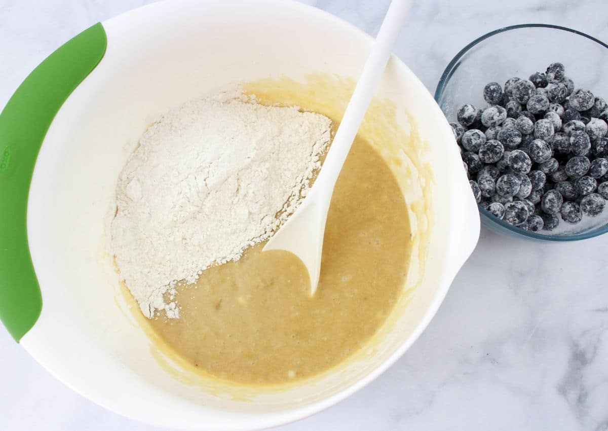 dry ingredients being added to wet ingredients in a large bowl.