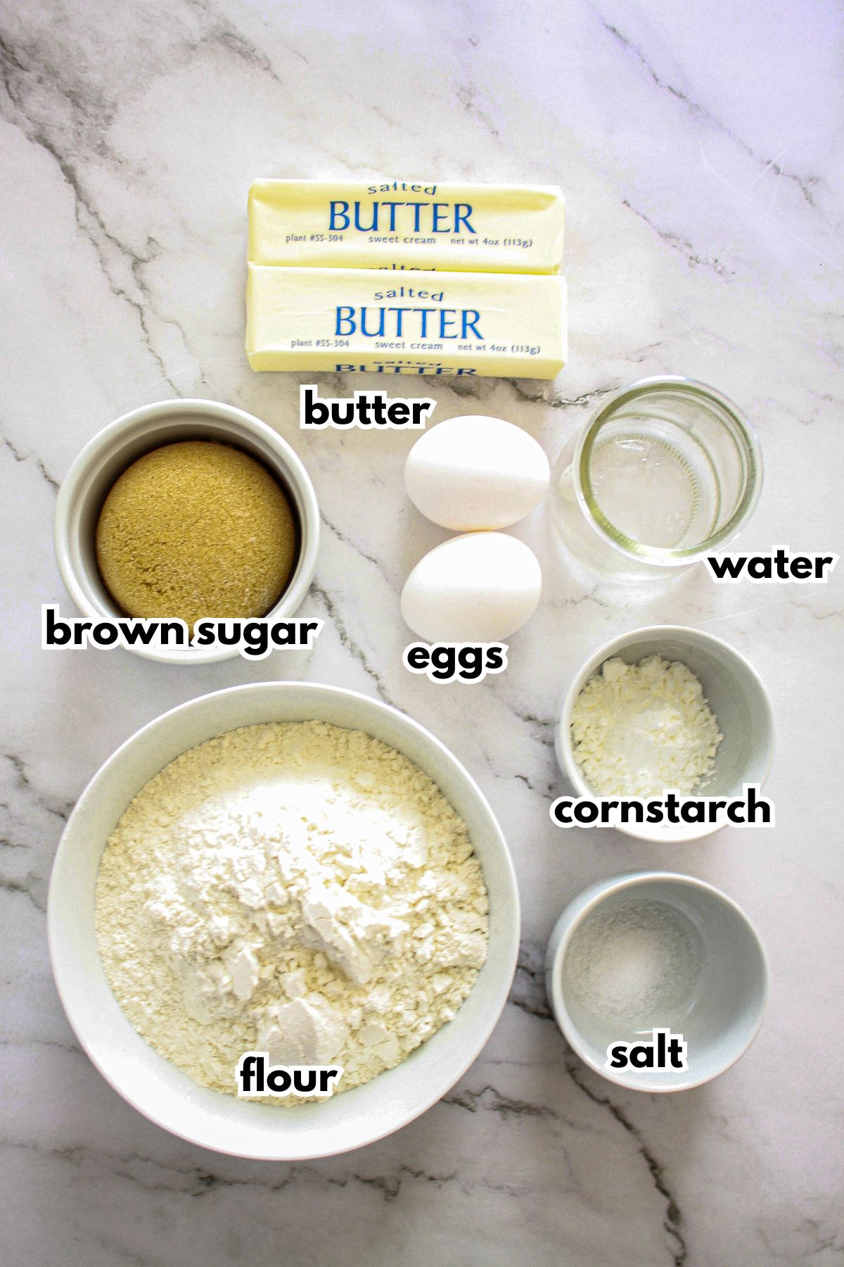 butter, eggs, and bowls of brown sugar, flour, water, cornstarch, and salt on a counter.