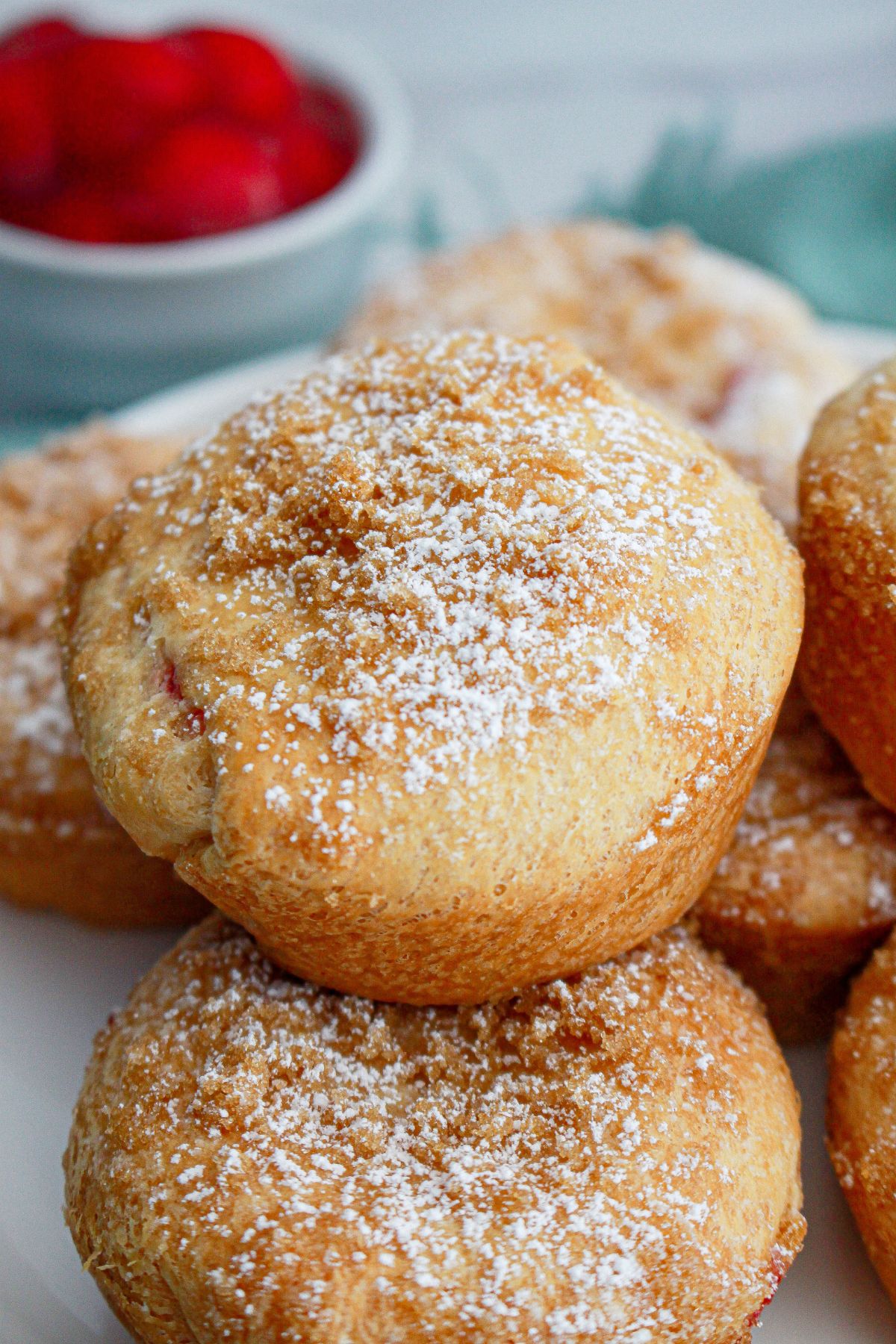 cherry cheesecake muffins stacked in a pyramid on a plate.