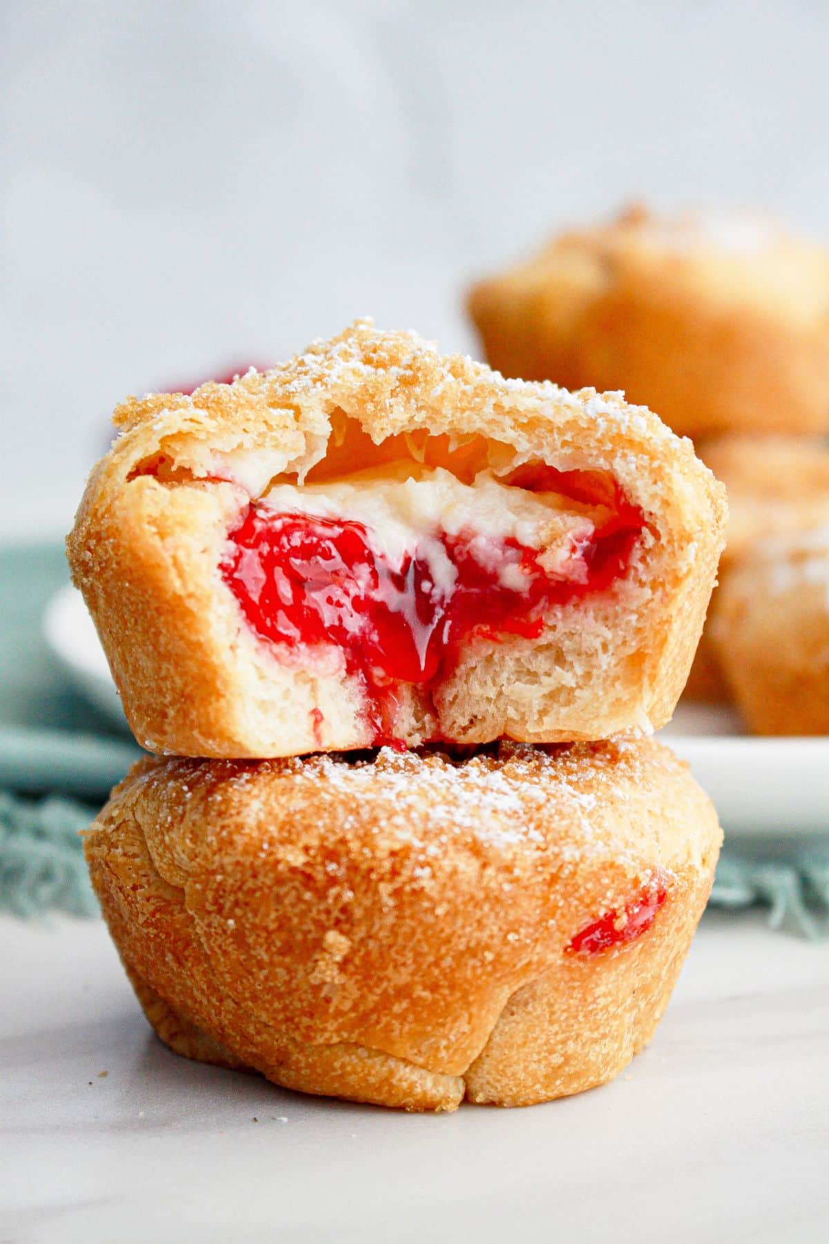 two cherry cheesecake muffins stacked on top of each other. The top one has a bite missing.