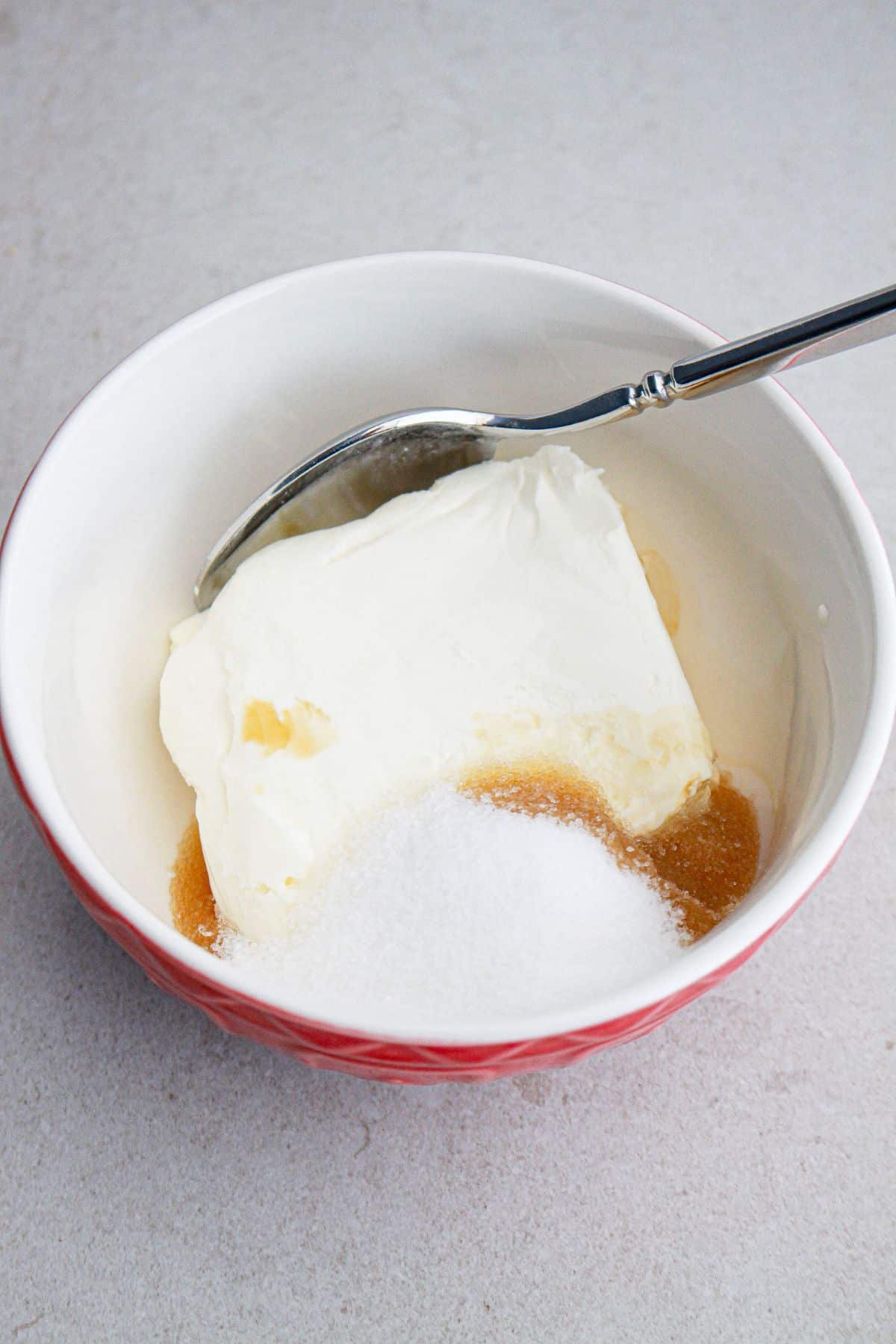 cream cheese, sugar, and vanilla extract being mixed in a small bowl.