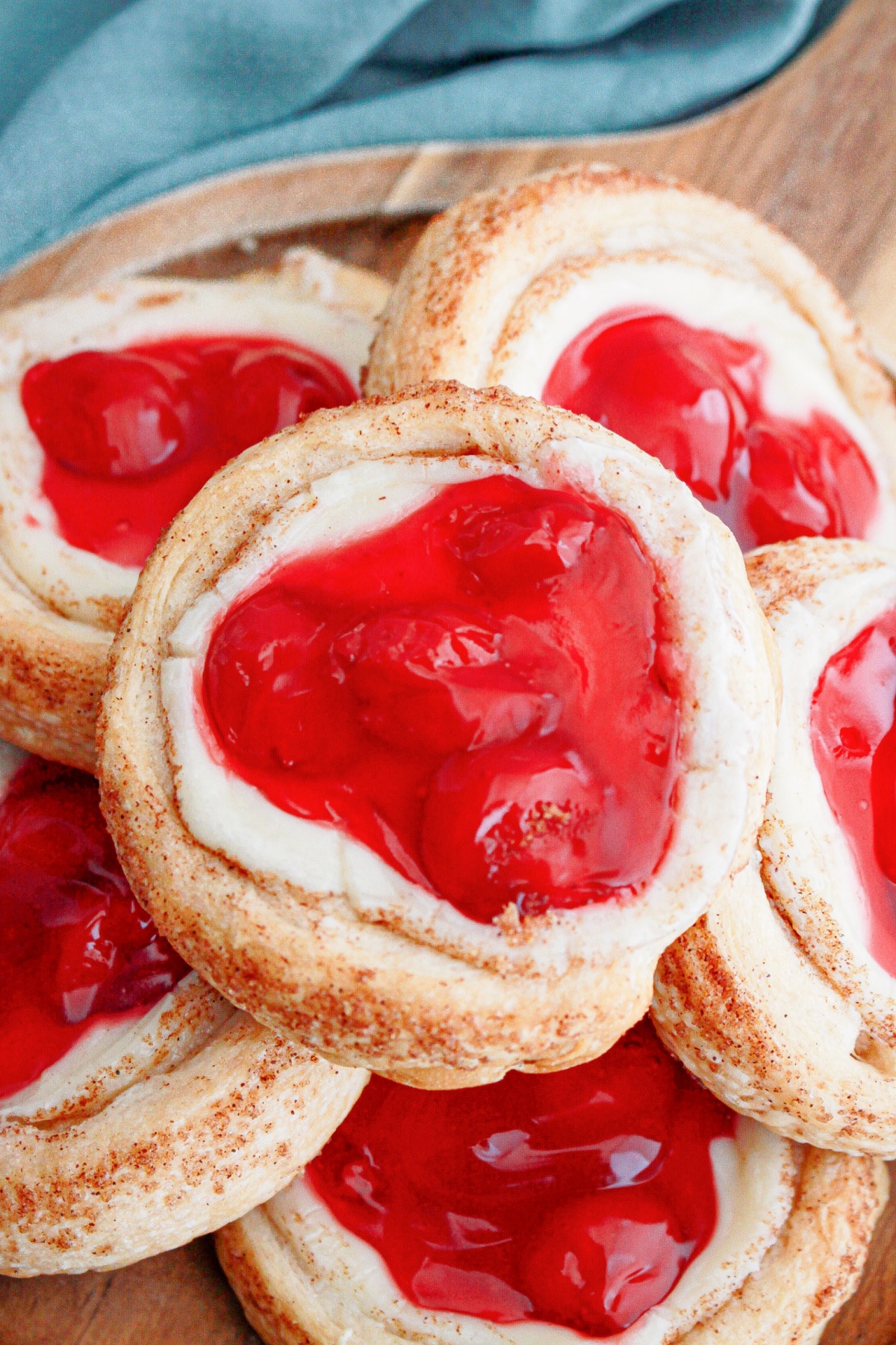 cherry danishes stacked on a wooden cake stand.