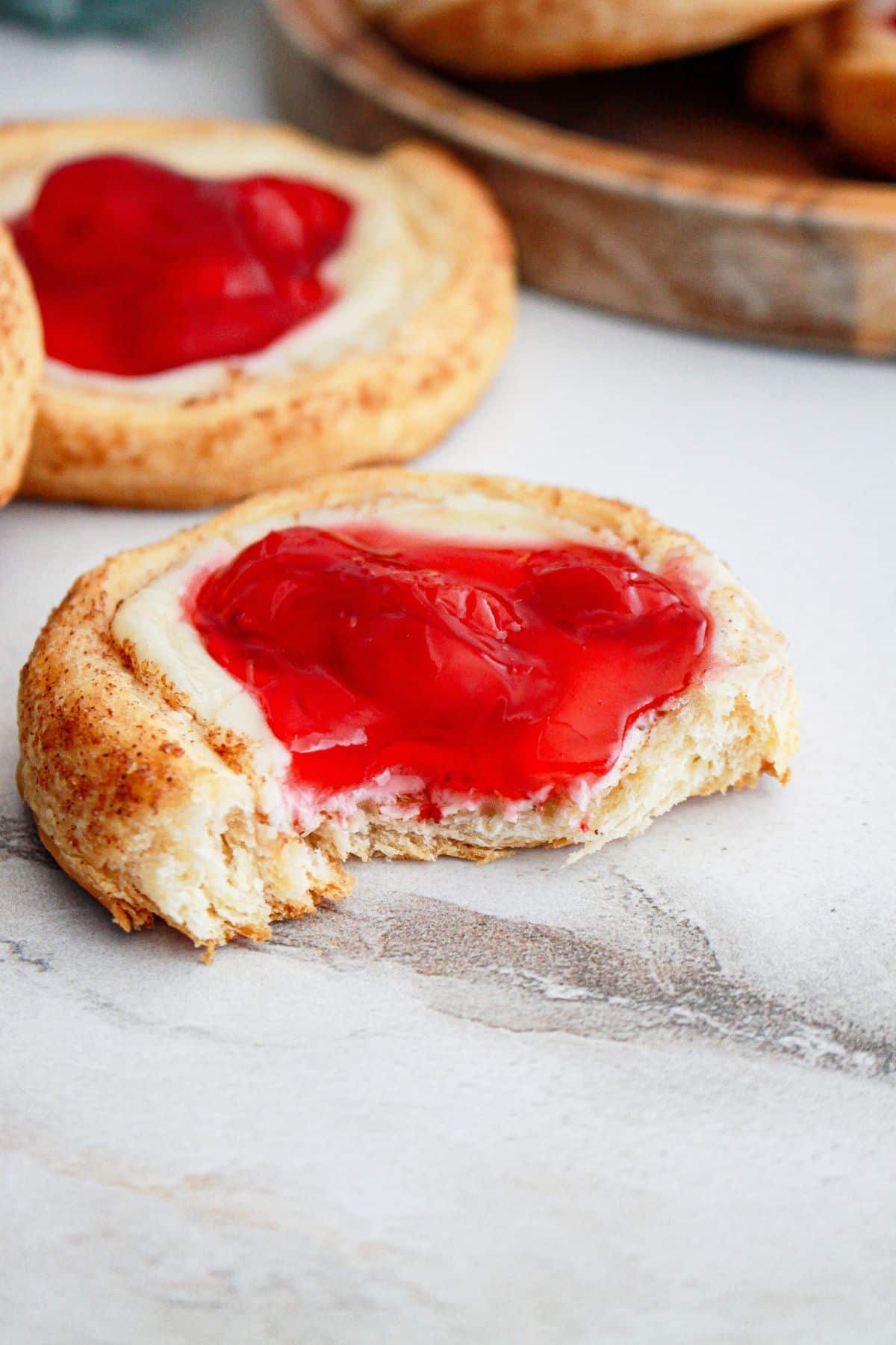 cherry danish on a marble counter with a bite missing.