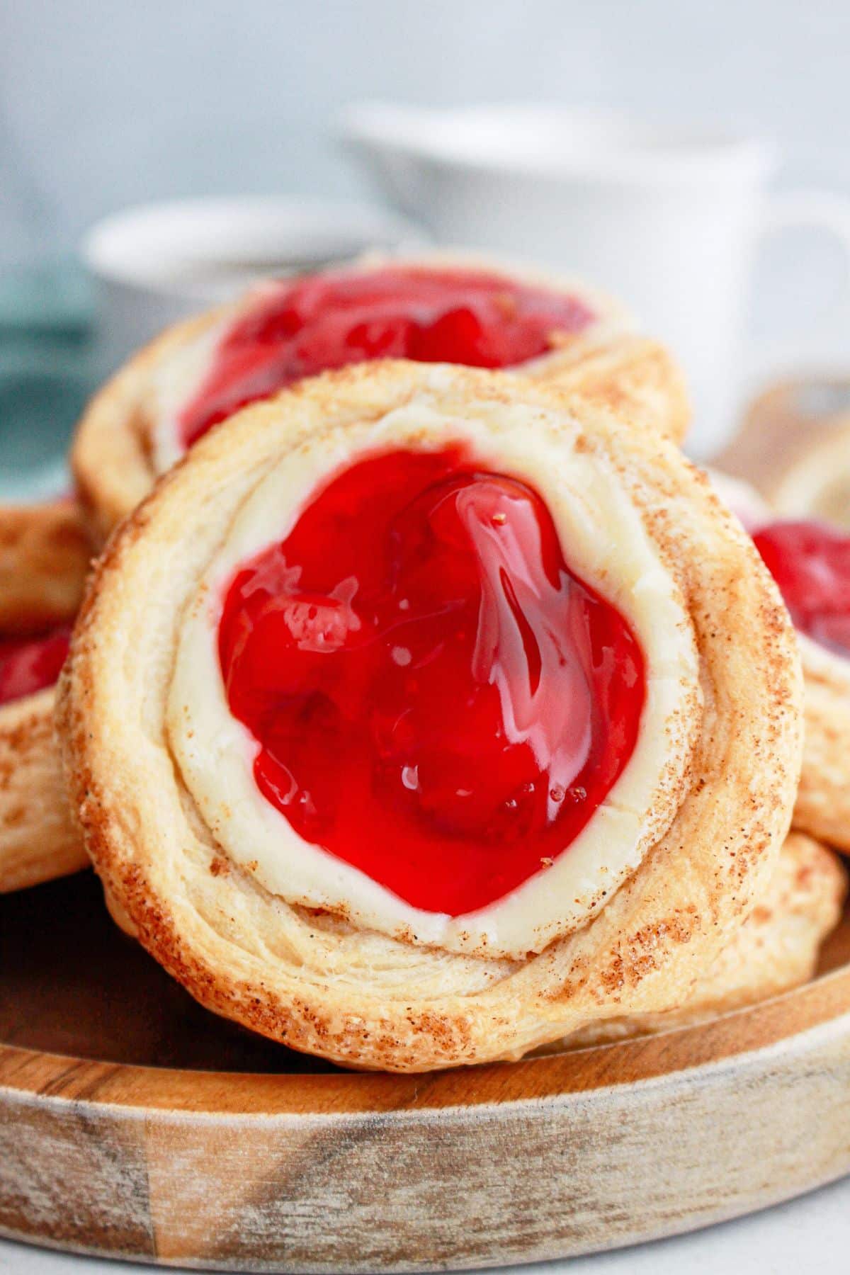 cherry danishes stacked on a wooden cake stand.