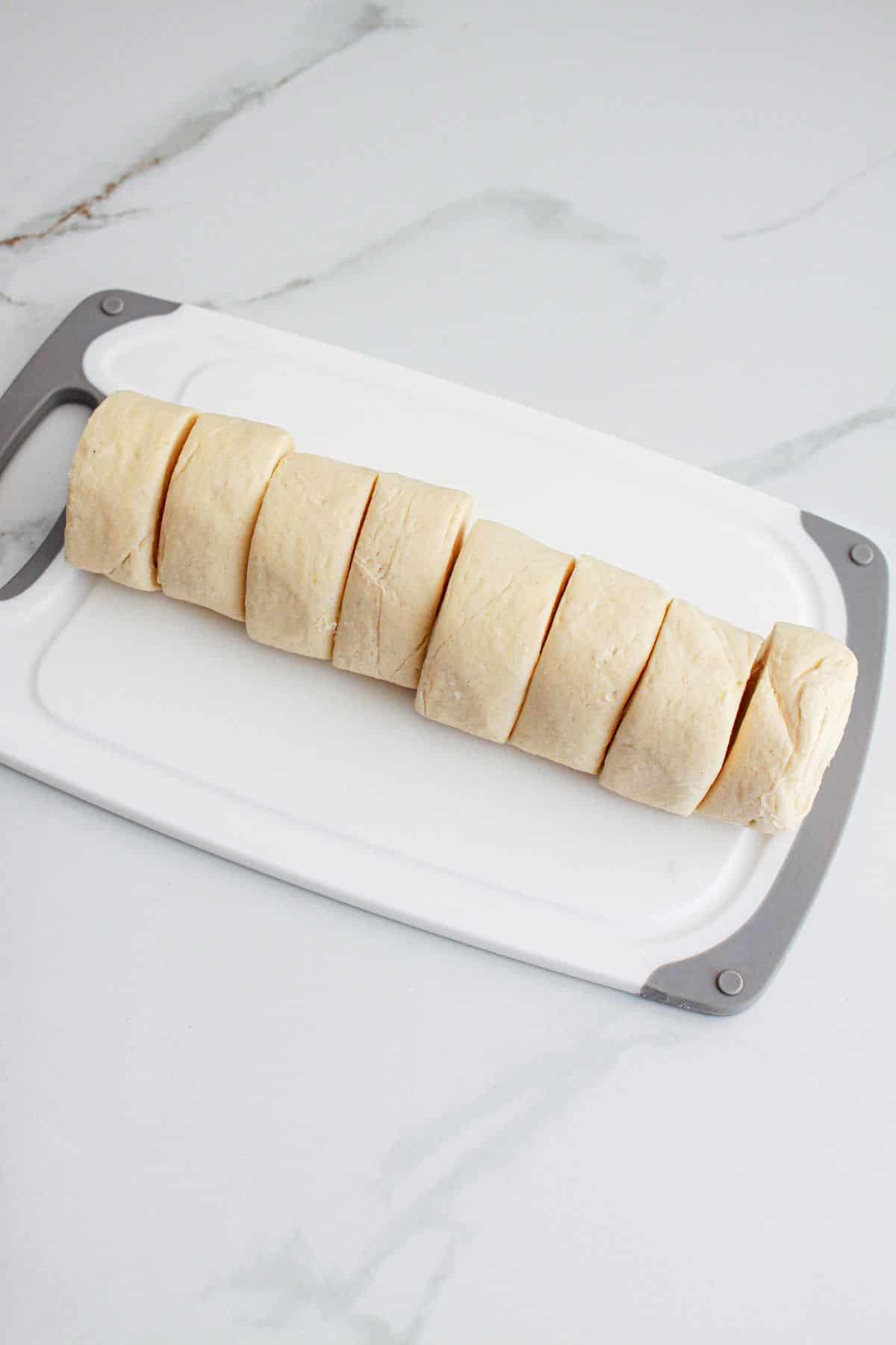crescent rolls being sliced on a cutting board.