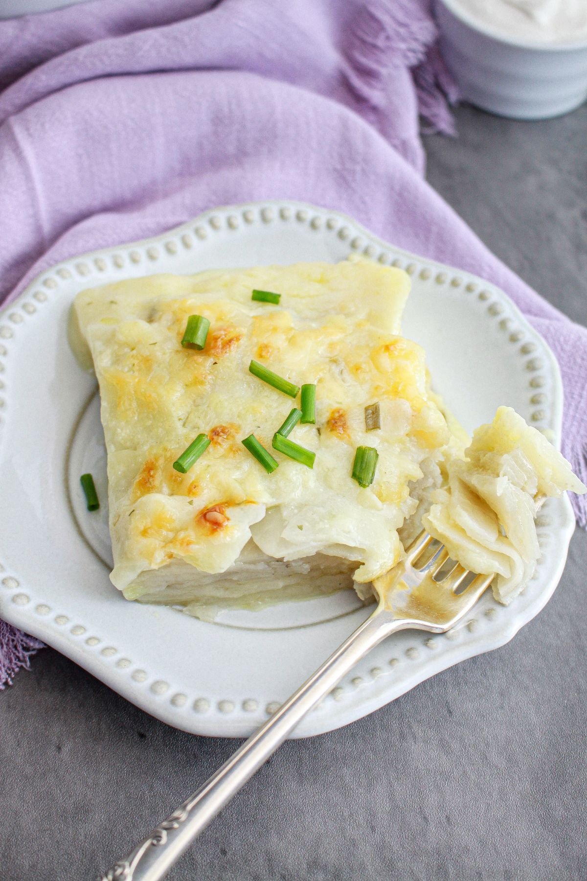 slice of sour cream and chive scalloped potatoes on a plate.