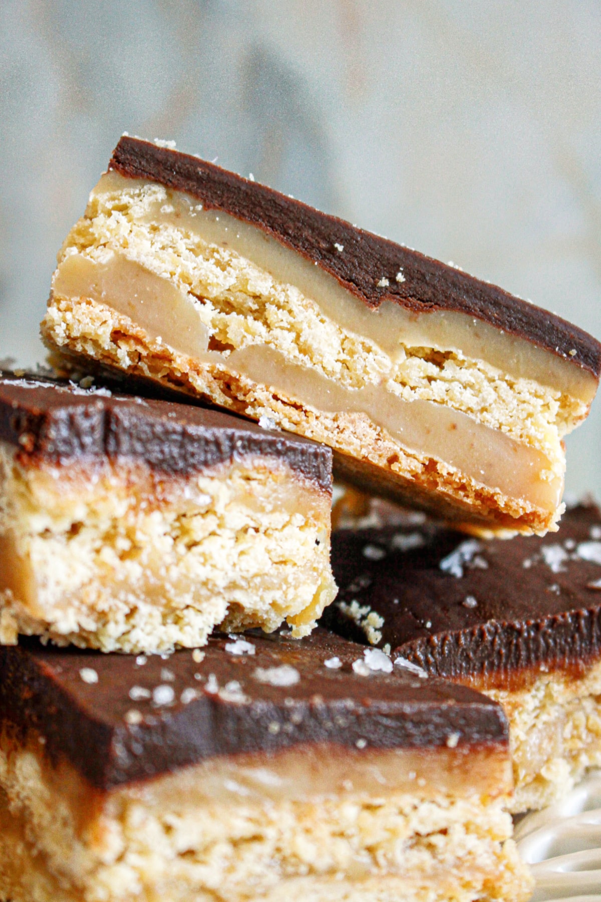 four chocolate caramel bars on a plate.