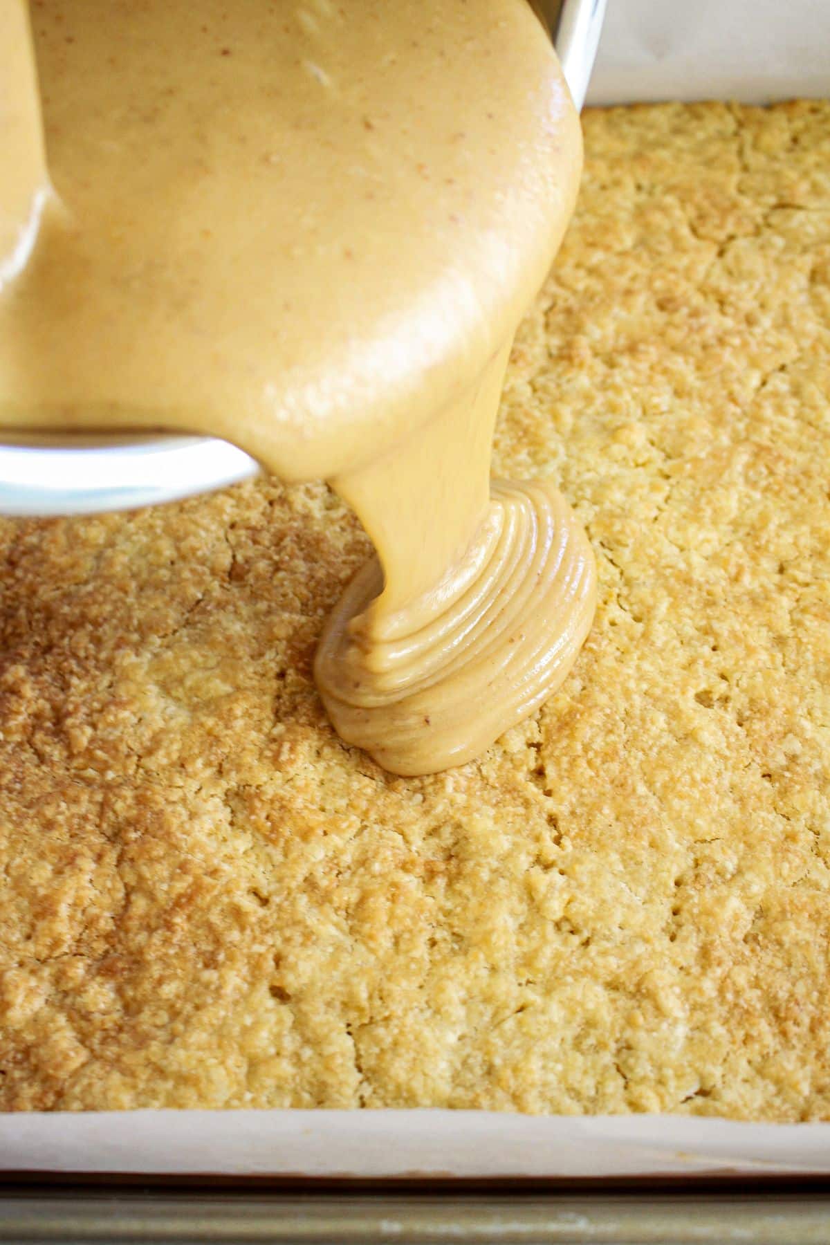 caramel layer being spread on top of cooled crust.