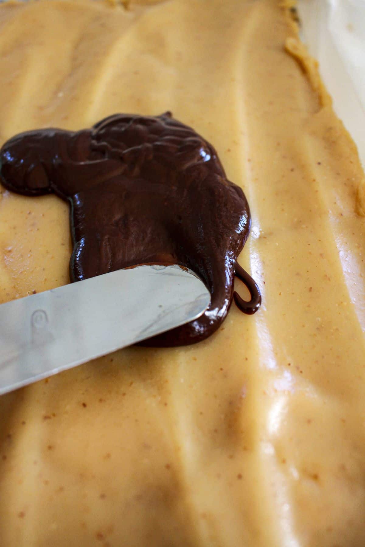 chocolate being spread on top of a caramel layer.