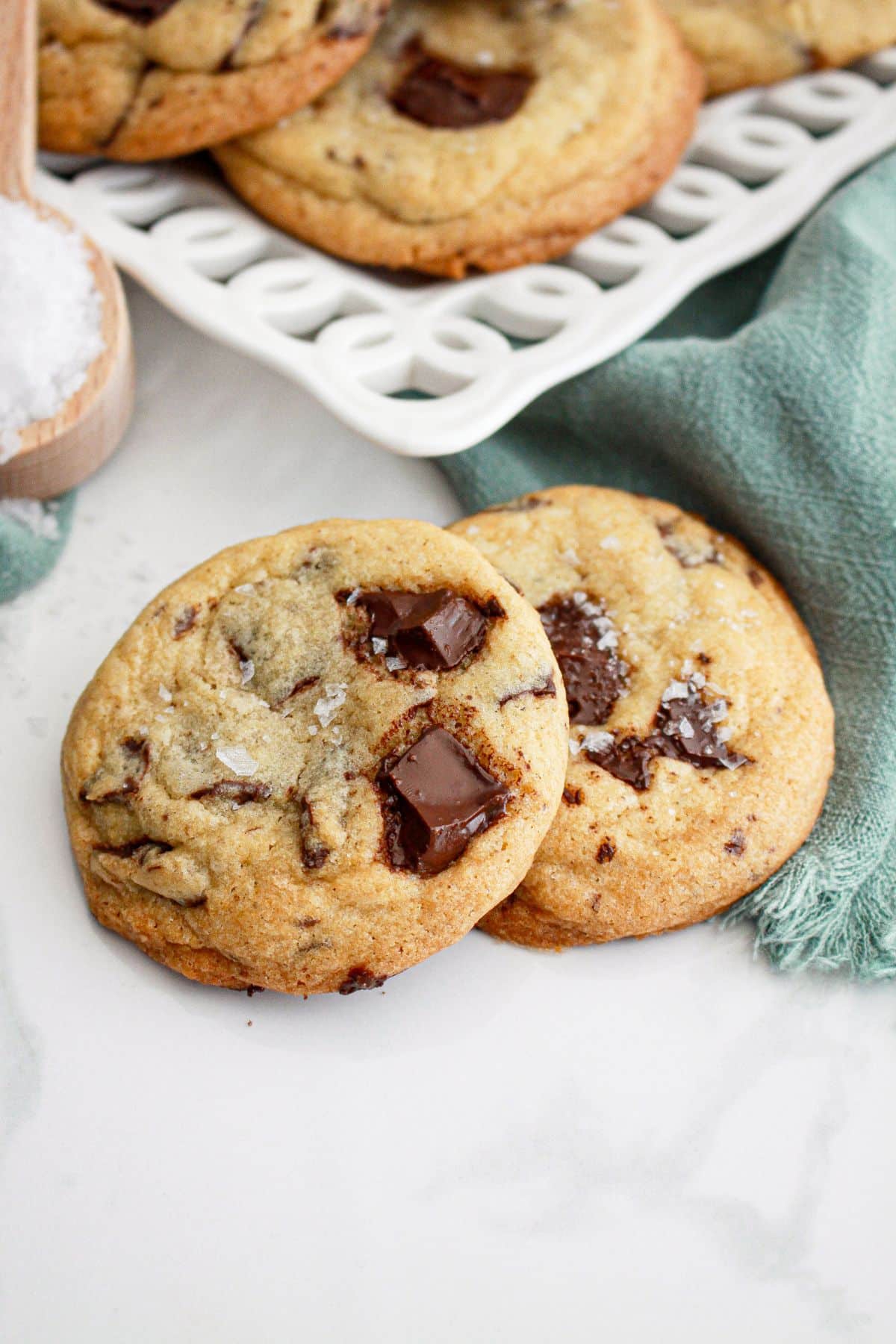 two chocolate chunk sea salt cookies on a marble counter.