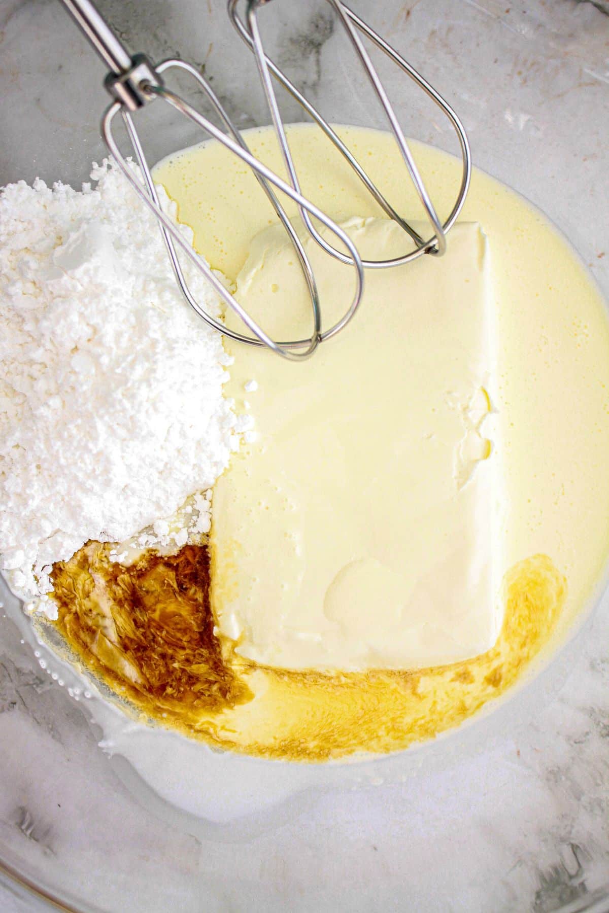cream cheese, powdered sugar, condensed milk, and vanilla extract in a mixing bowl.