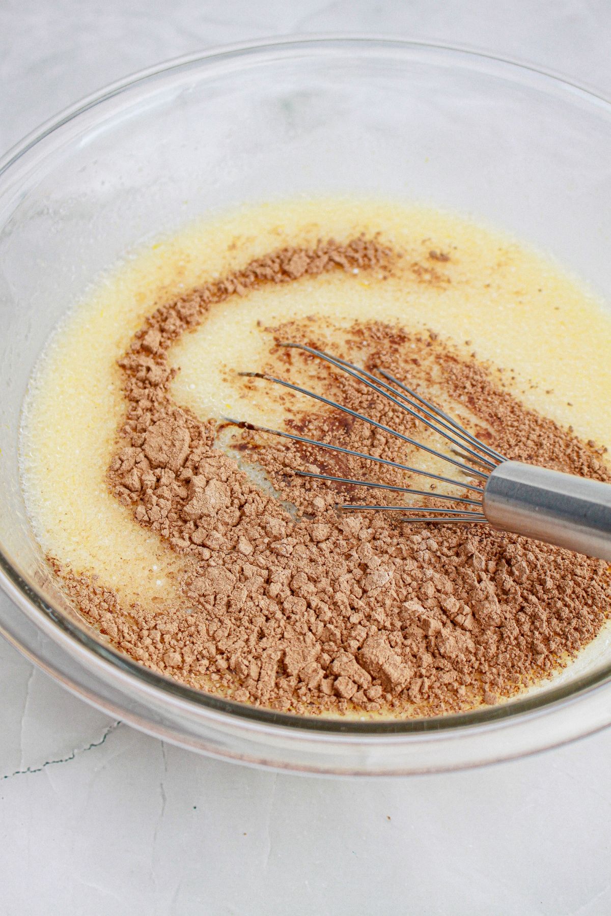 cake batter being whisked in a glass baking dish.