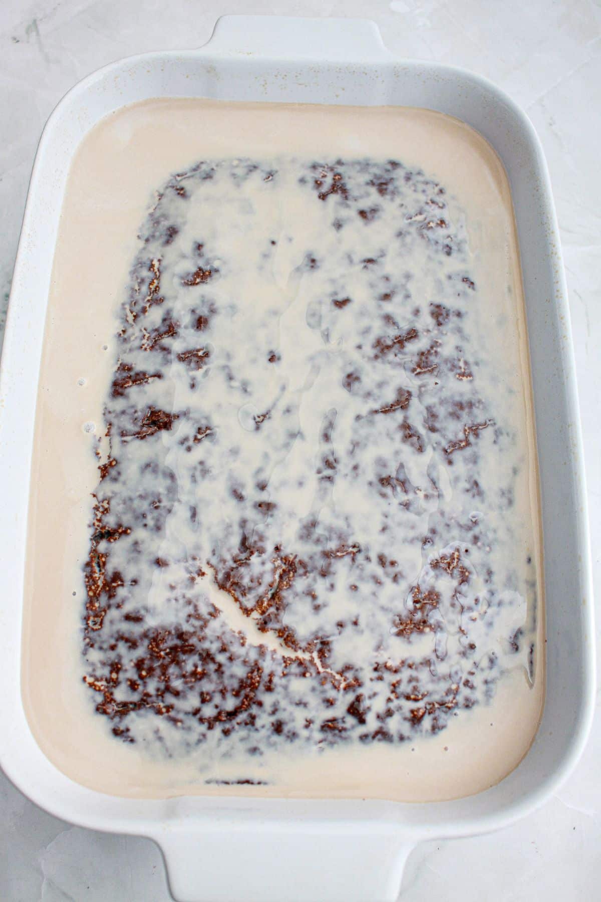 three milk being poured on top of the cake in a baking dish.
