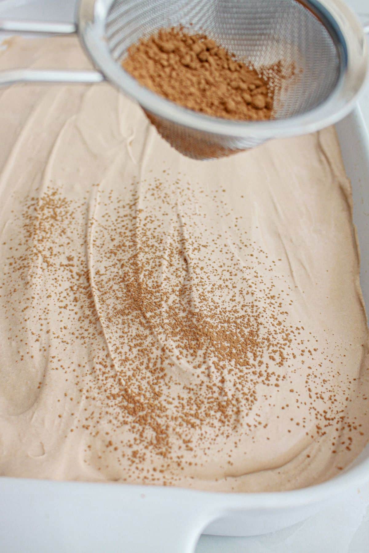 cocoa powder being dusted on top of a cake.