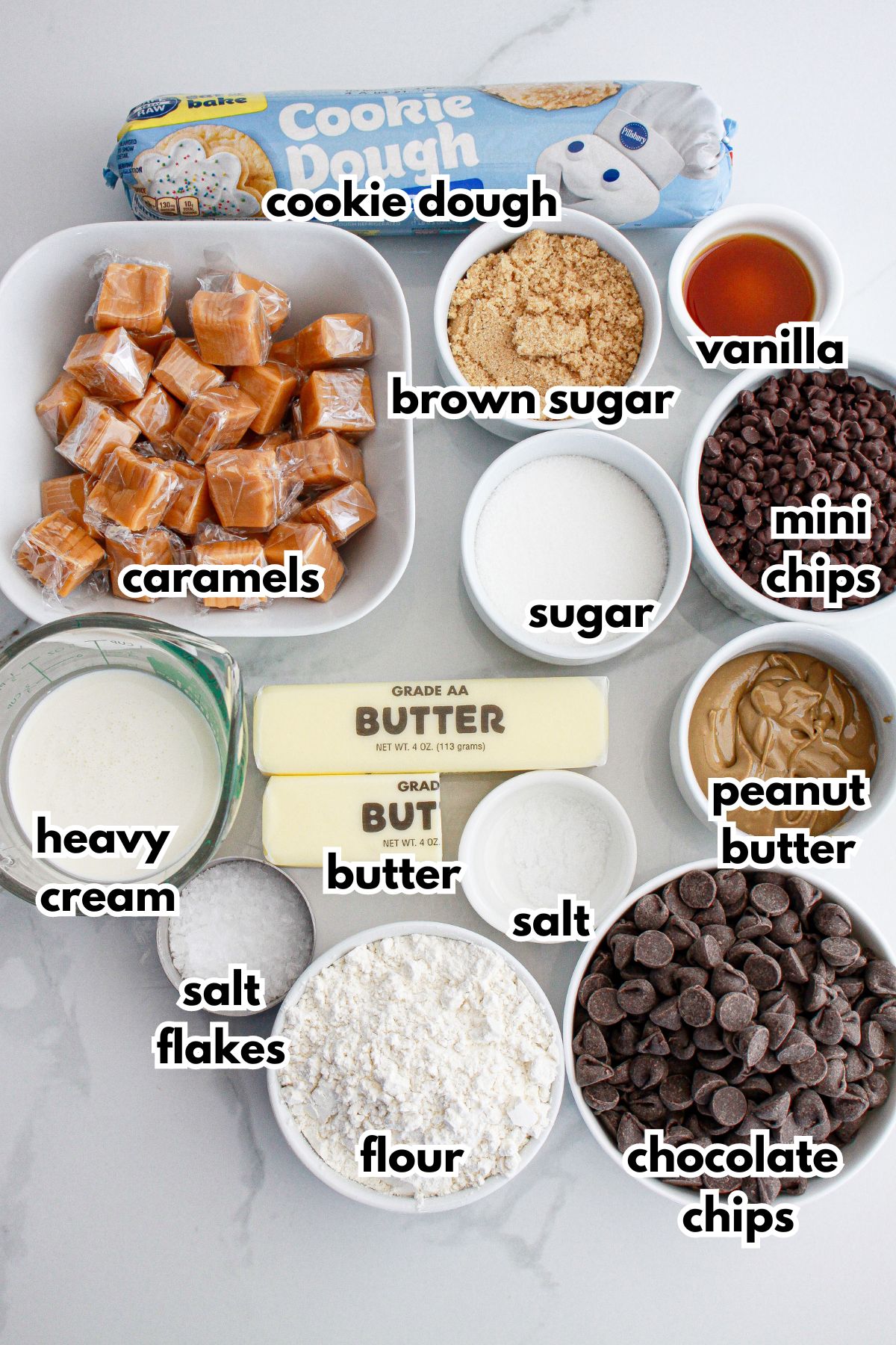 bowls of ingredients needed to make salted caramel cookie dough billionaire bars on a counter.