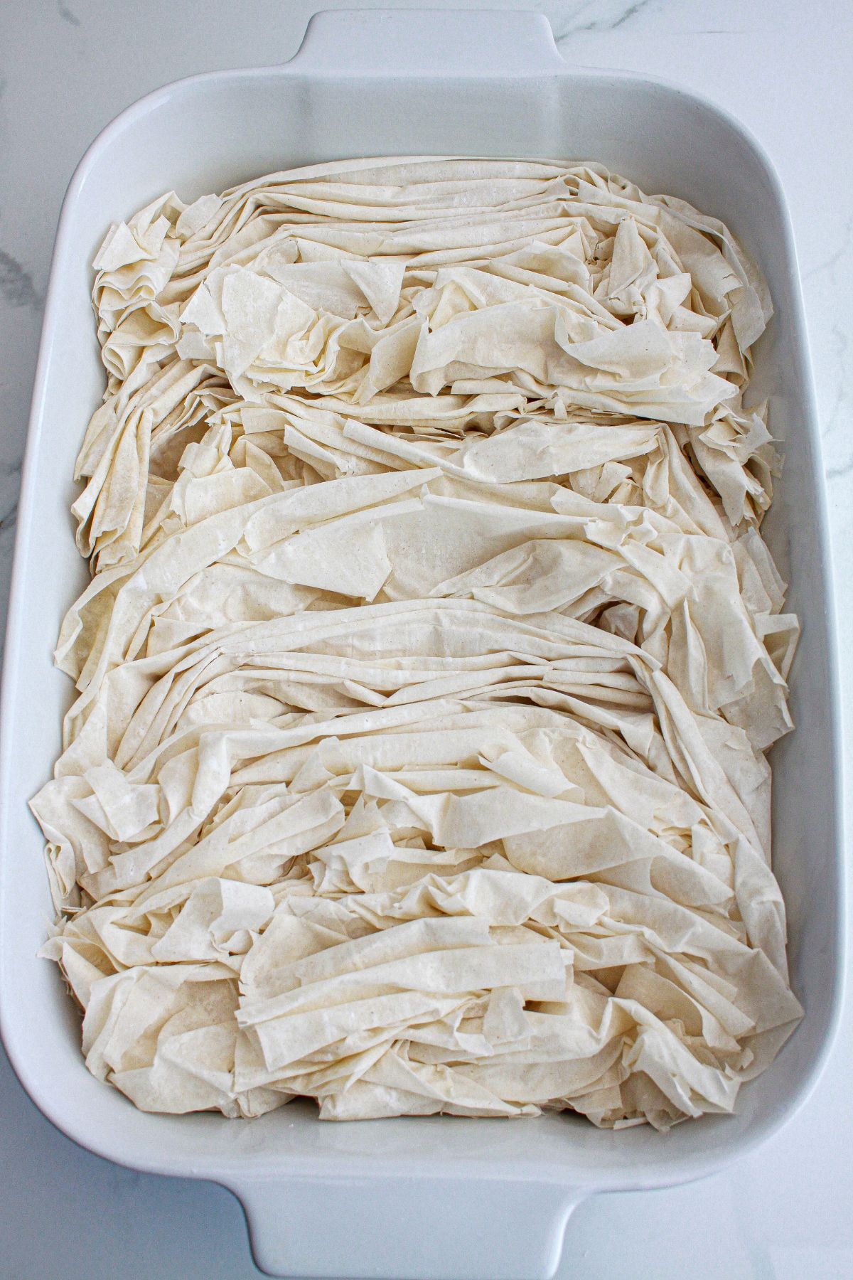 phyllo dough being scrunched into a baking dish.
