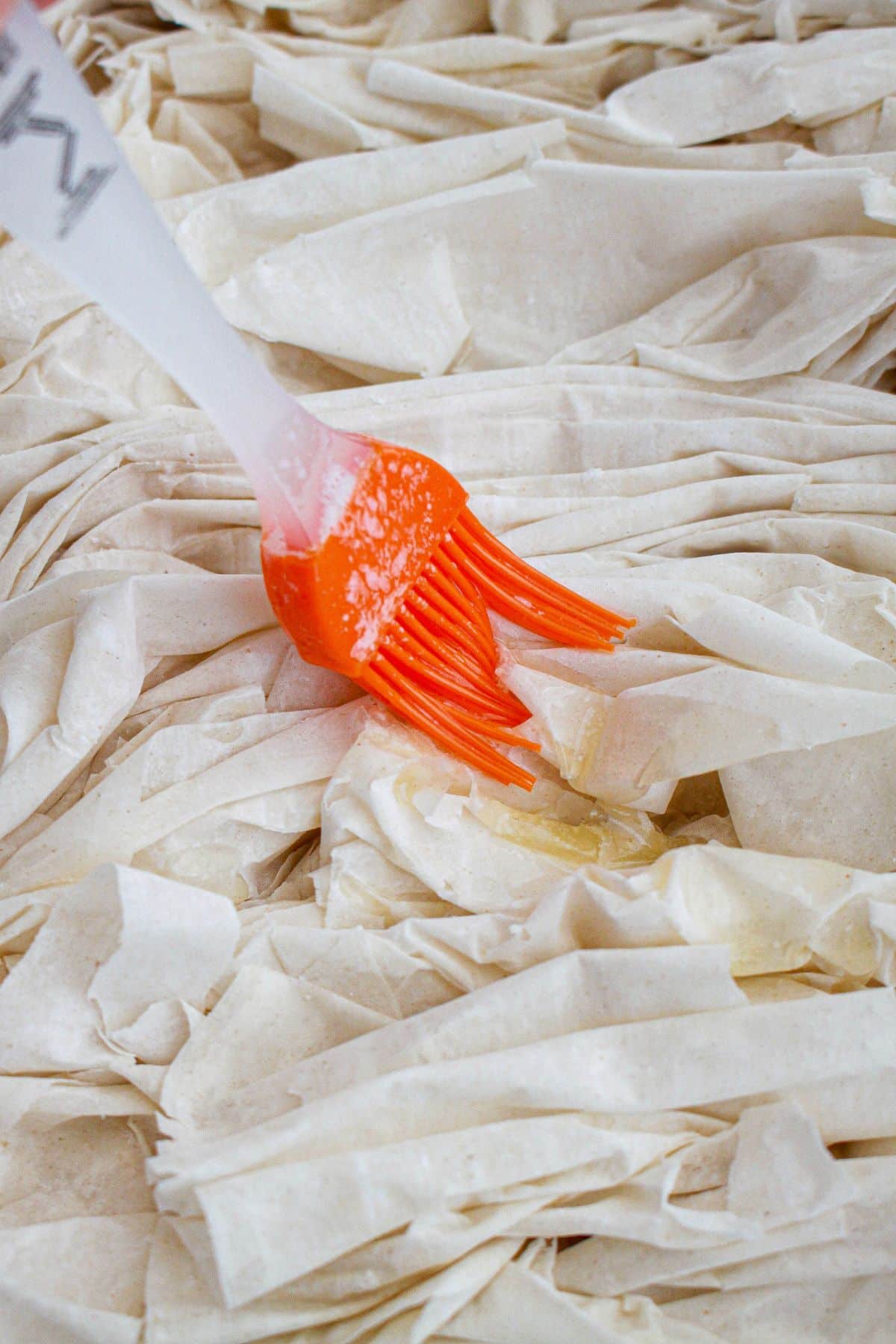 melted butter being brushed on top of phyllo dough.