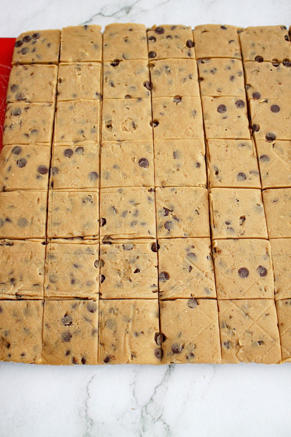 shortbread being cut into squares on a baking mat.