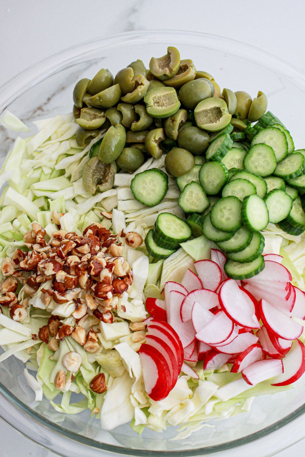 salad ingredients being added in a large bowl.