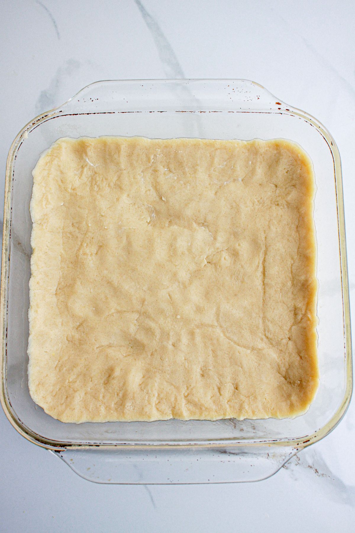 crust being pressed into a glass baking dish.