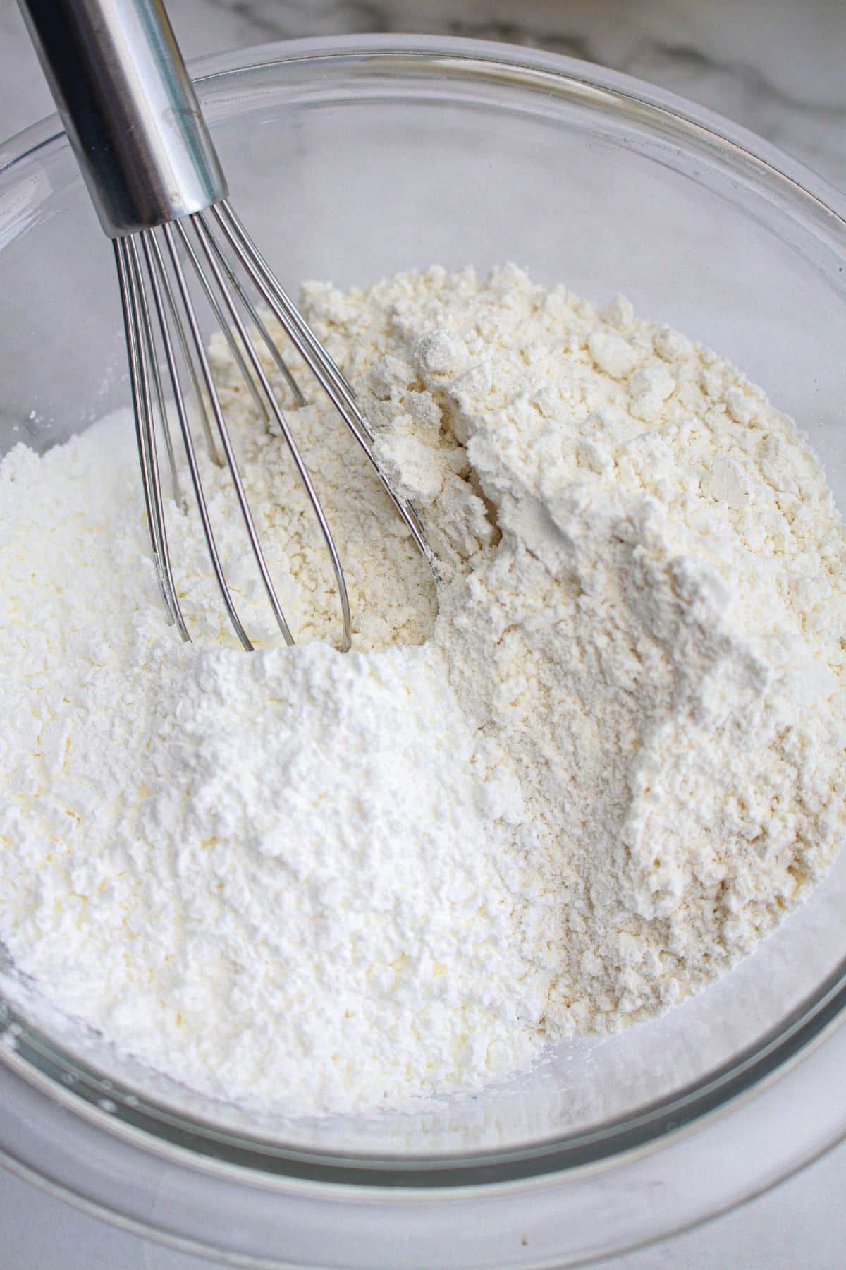 dry ingredients being whisked together in a glass mixing bowl.
