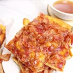 pieces of maple bacon caramel crack stacked on top of each other on a plate.