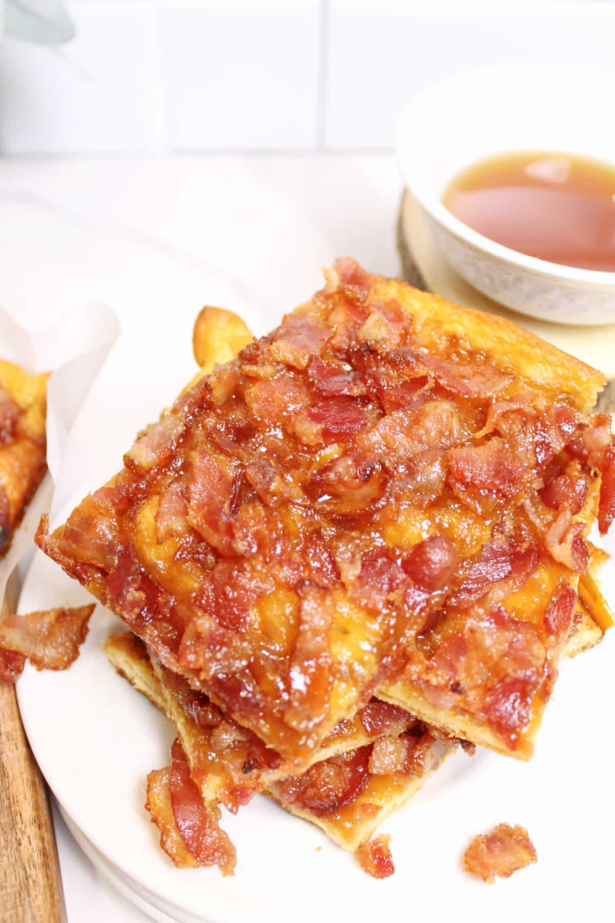 pieces of maple bacon caramel crack stacked on top of each other on a plate.