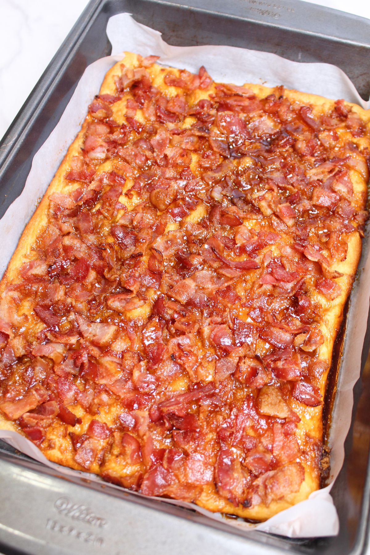 maple bacon caramel crack cooling in a parchment paper lined baking dish.