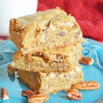 three maple pecan blondies stacked on table on a plate.