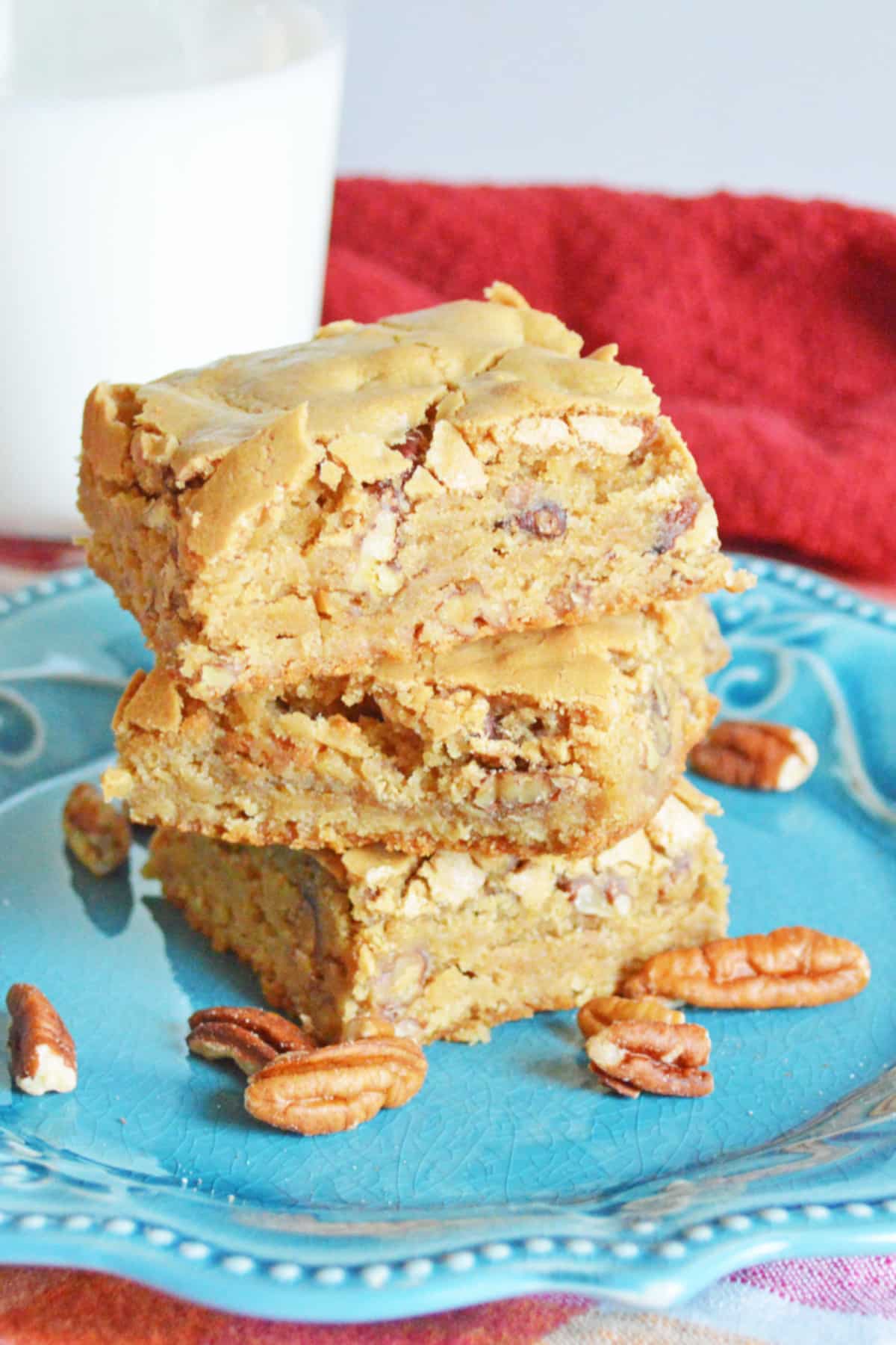three maple pecan blondies stacked on table on a plate.