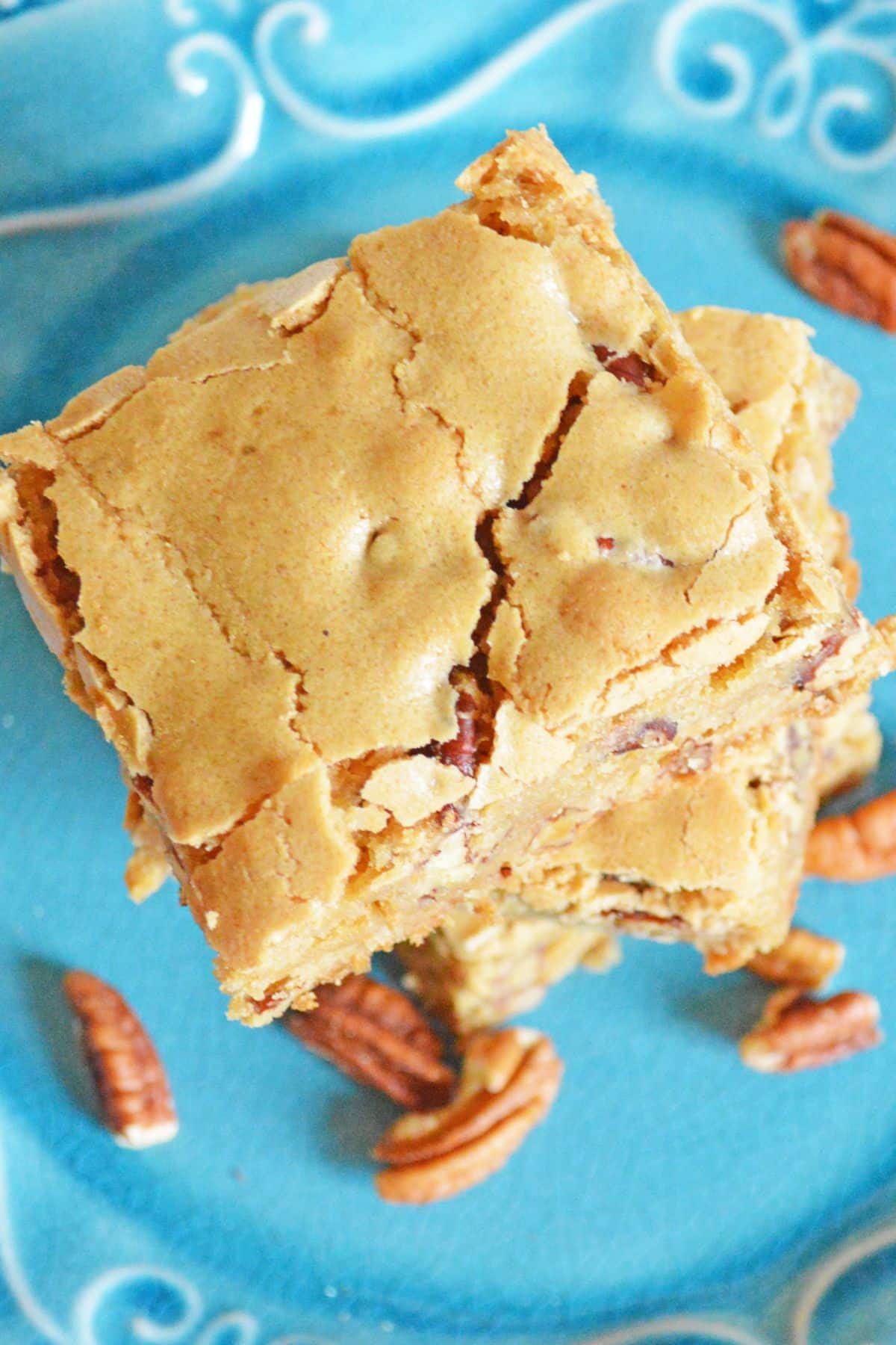 three maple pecan blondies stacked on table on a plate.