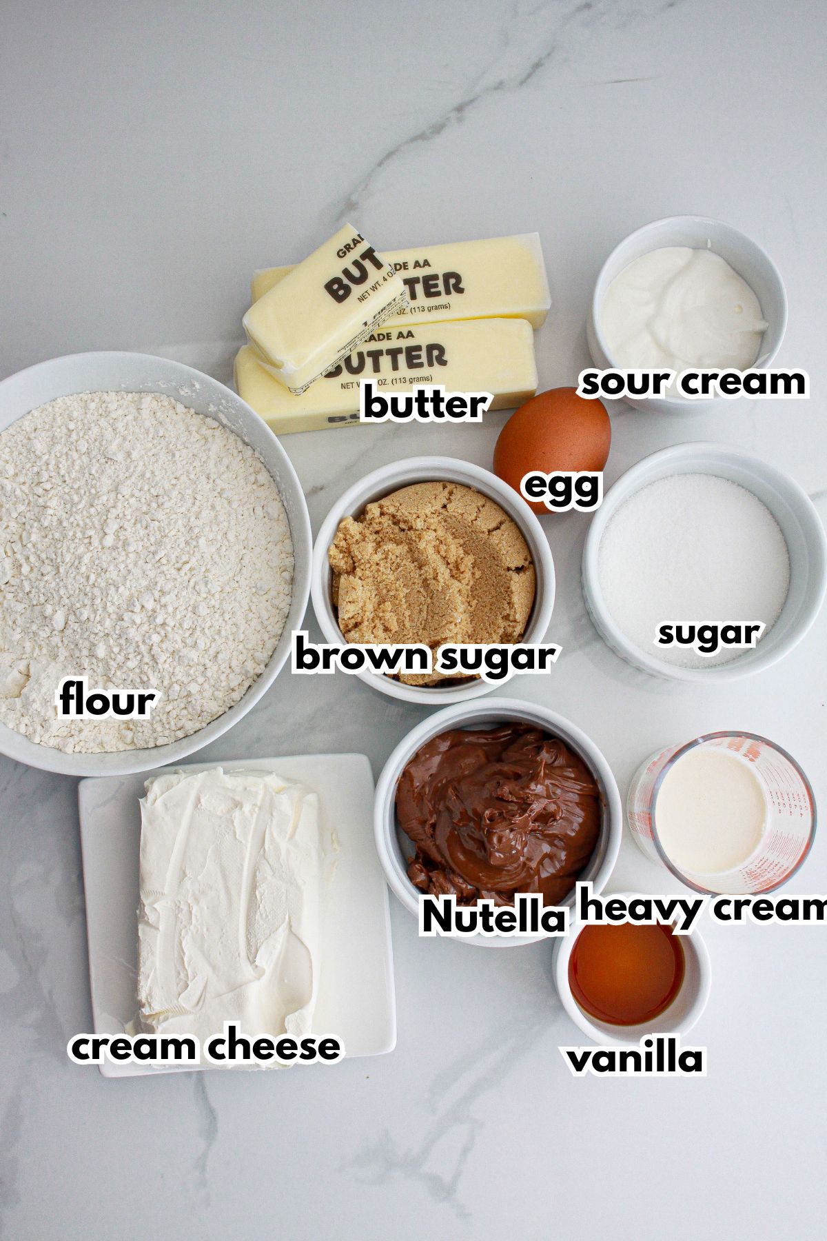 bowls of butter, egg, sour cream, flour, brown sugar, sugar, cream cheese, nutella, heavy cream, and vanilla extract.