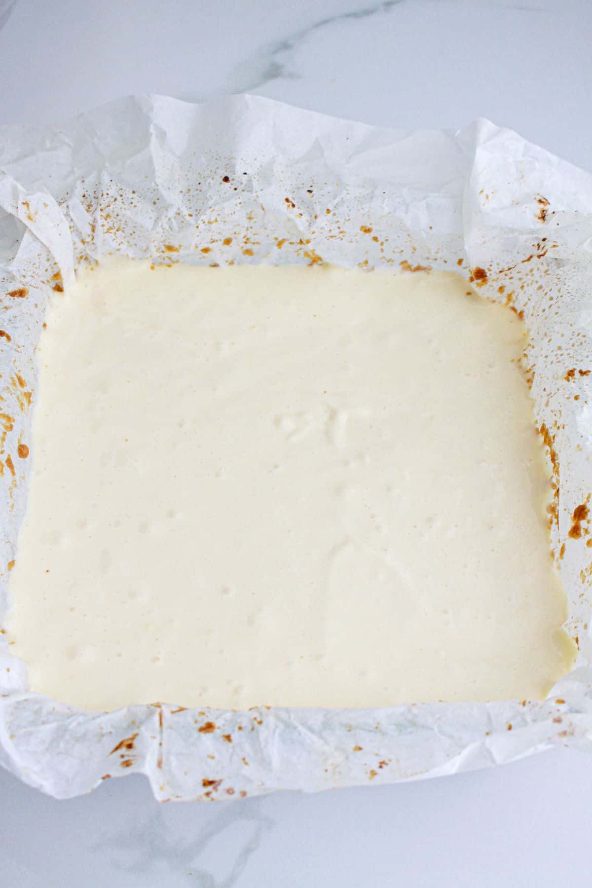 cheesecake batter in a parchment lined baking dish.