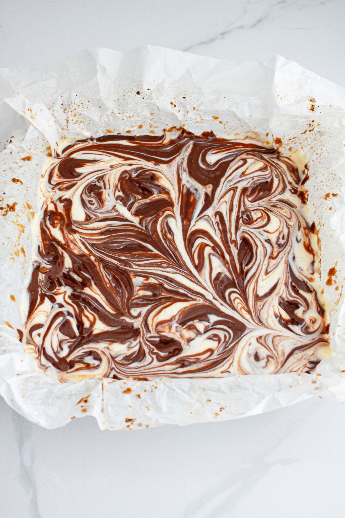 cheesecake bars in a parchment lined baking dish ready for the oven.