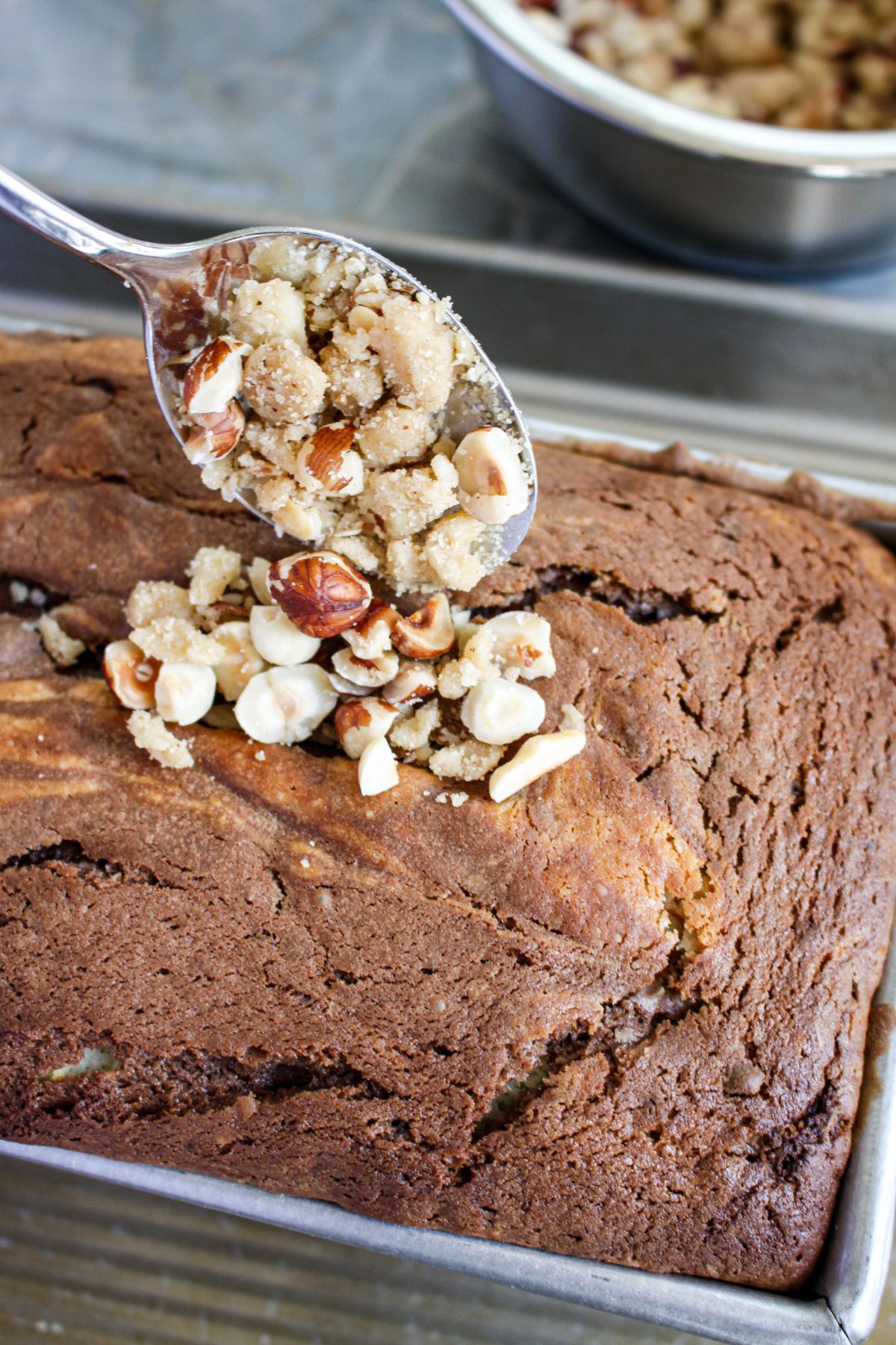 hazelnut crumble being added to the top of the bread.