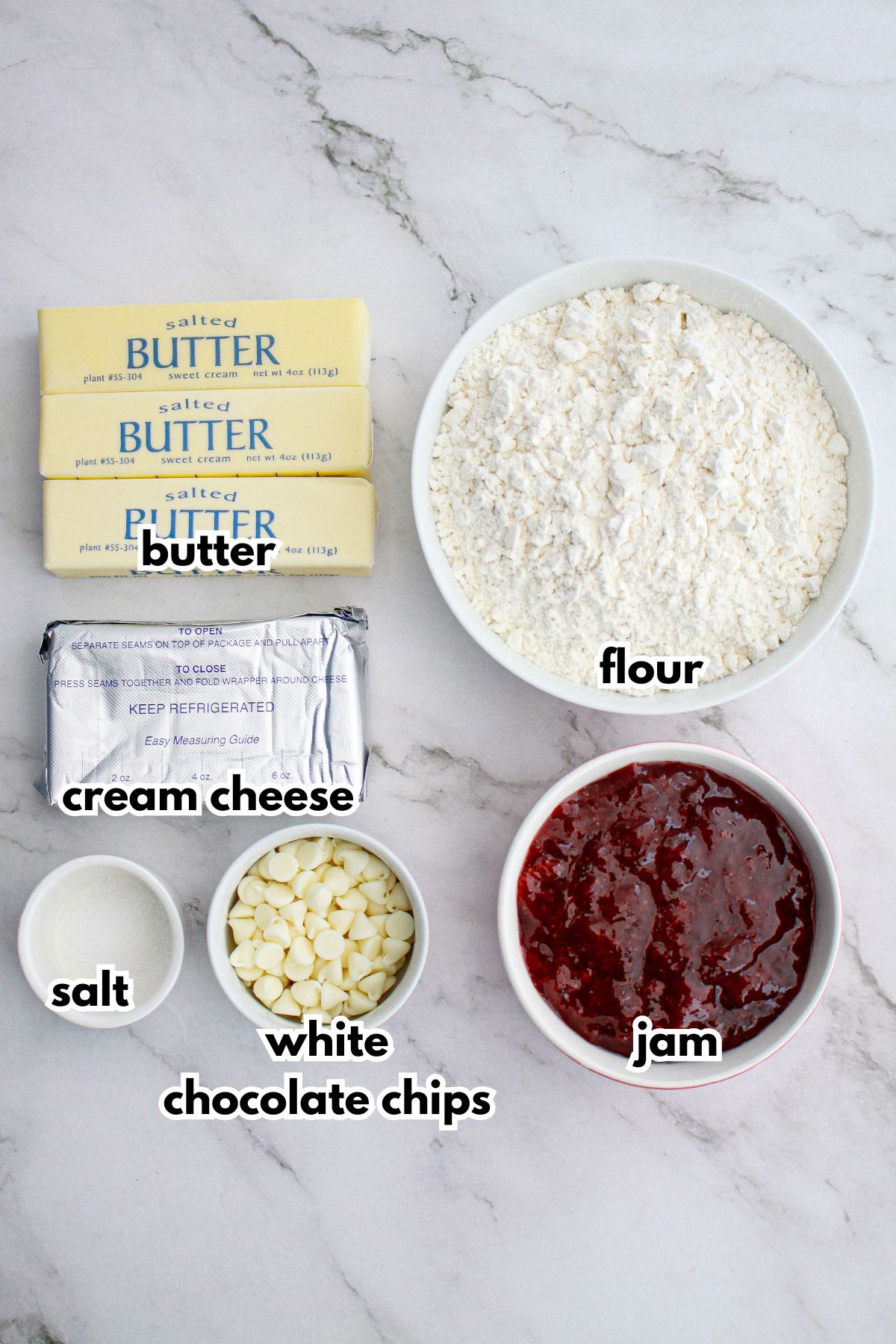 butter, cream cheese, flour, salt, white chocolate chips, and jam on a counter.