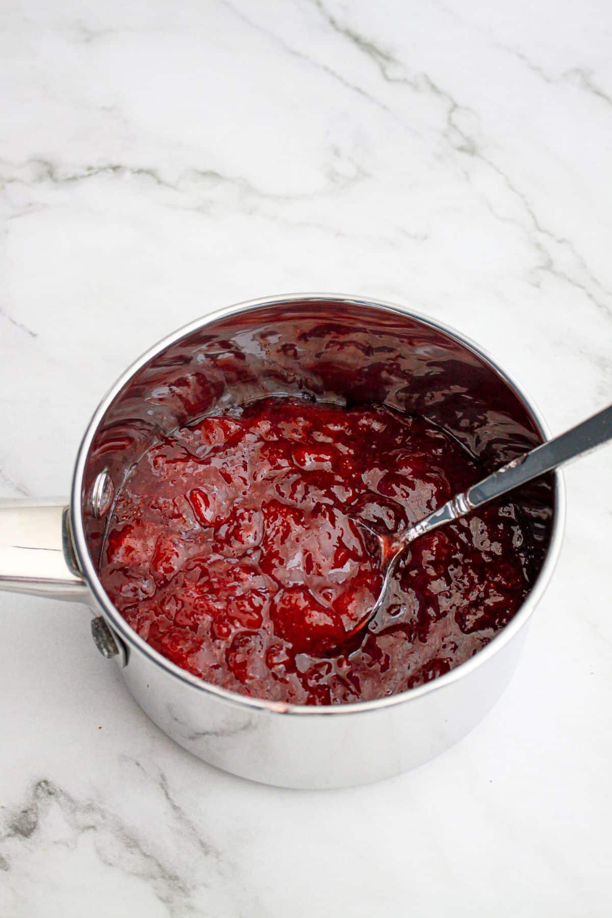 strawberry jam being heated in a saucepan.