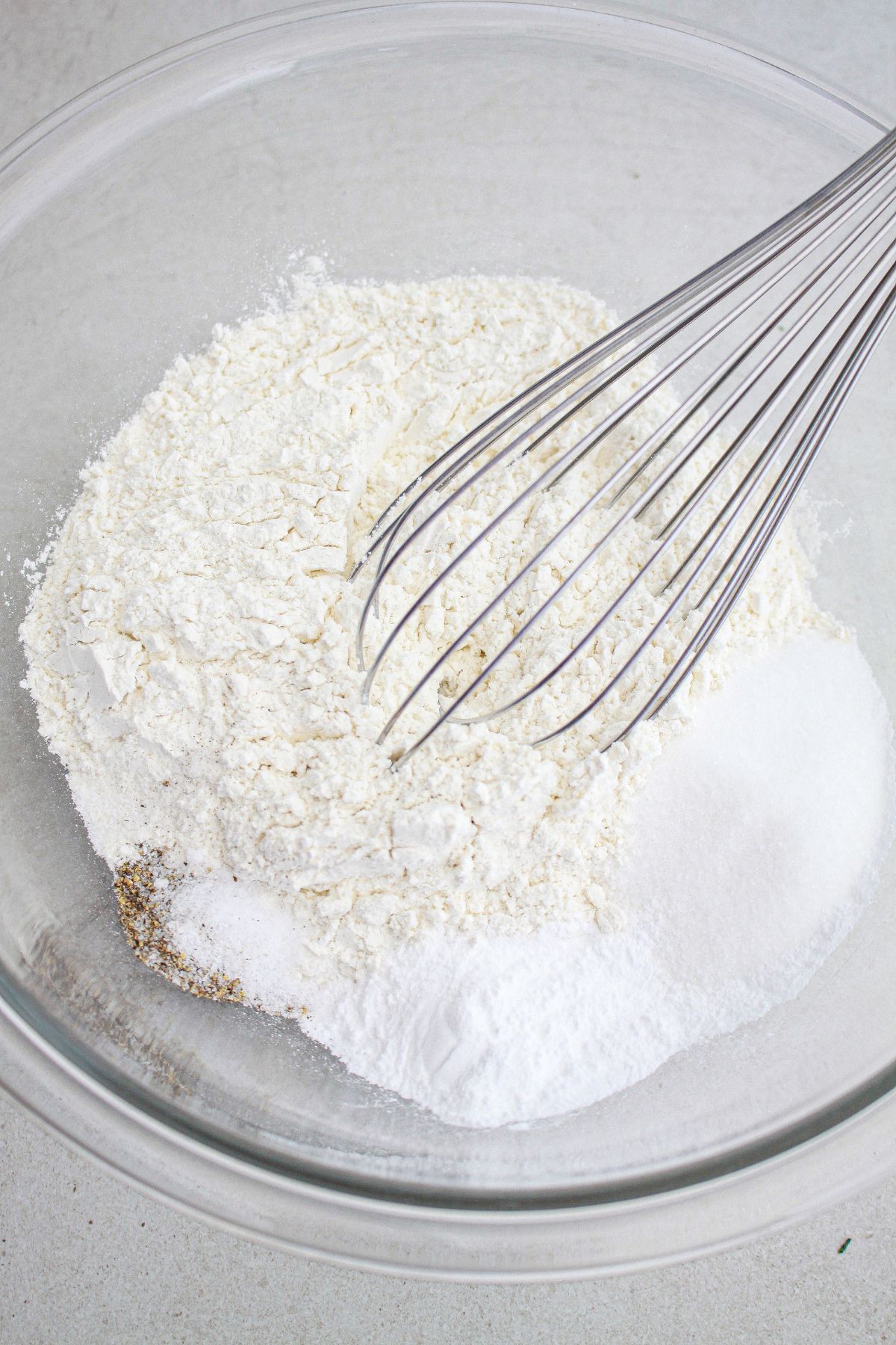 dry ingredients being whisked together in a glass mixing bowl.