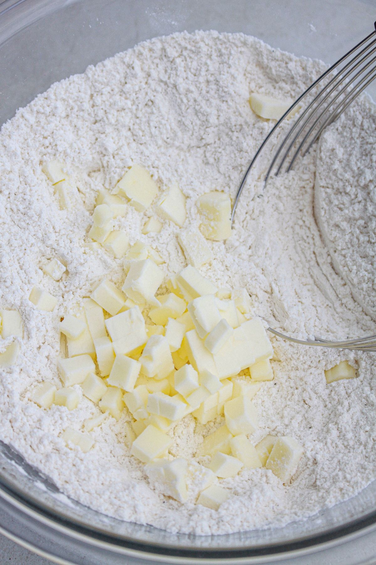 butter being added to dry ingredients with a pastry cutter.