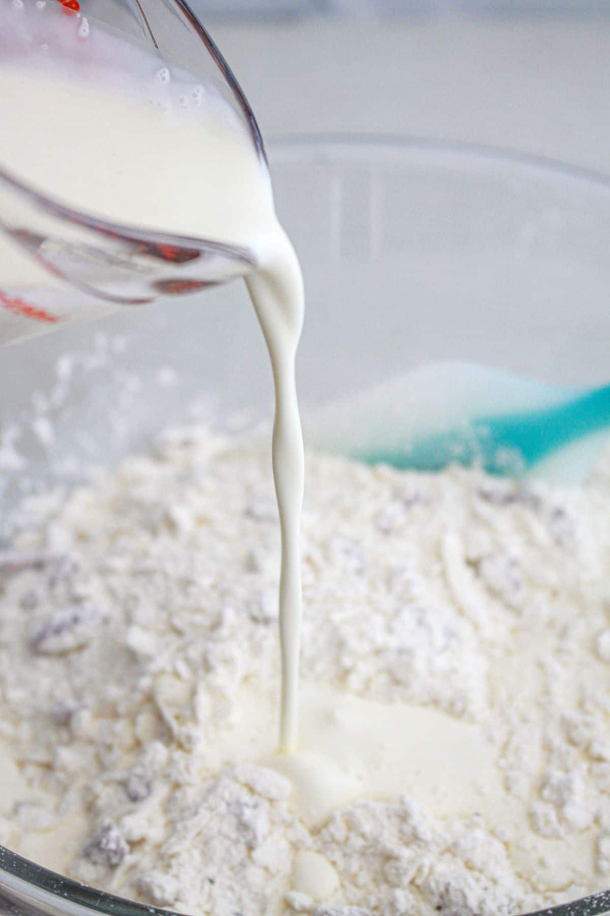 cream being poured into dry ingredients in a mixing bowl.
