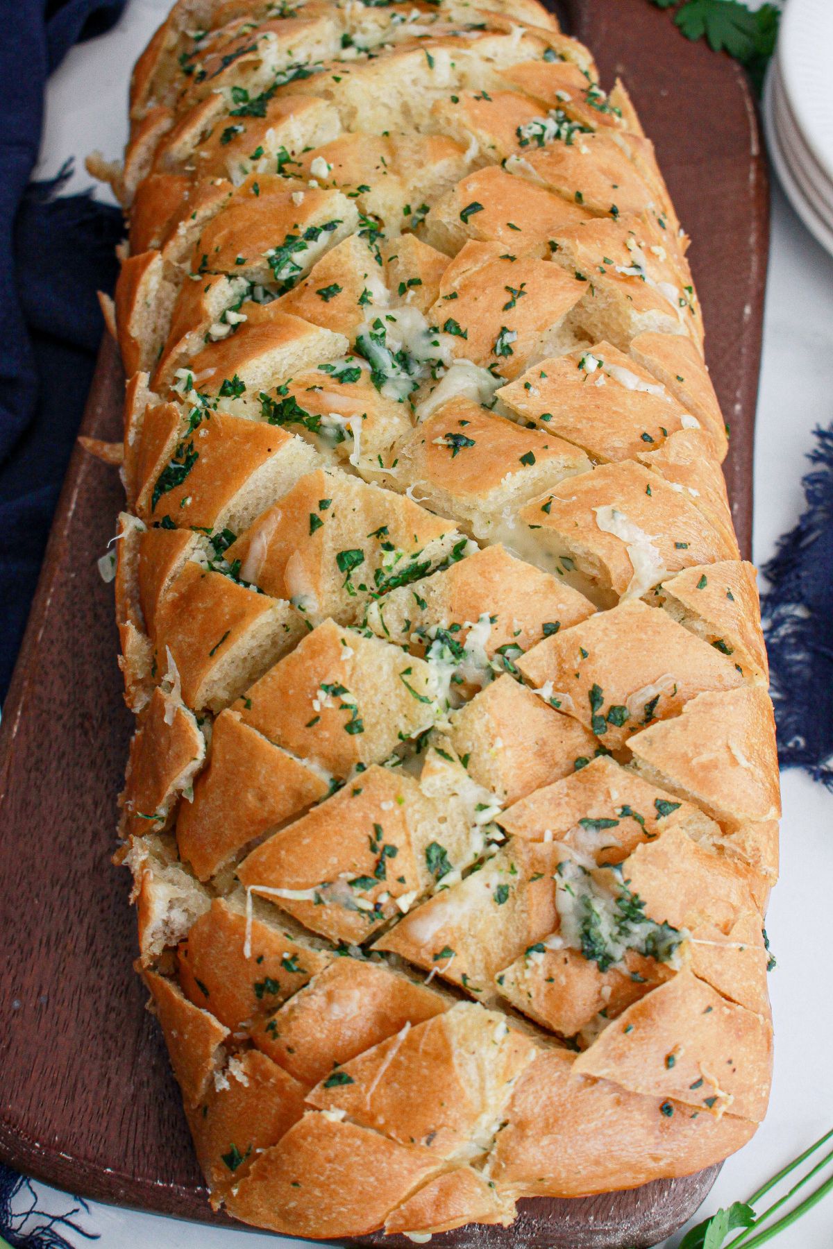 baked loaf of cheesy garlic bread on a wooden cutting board.